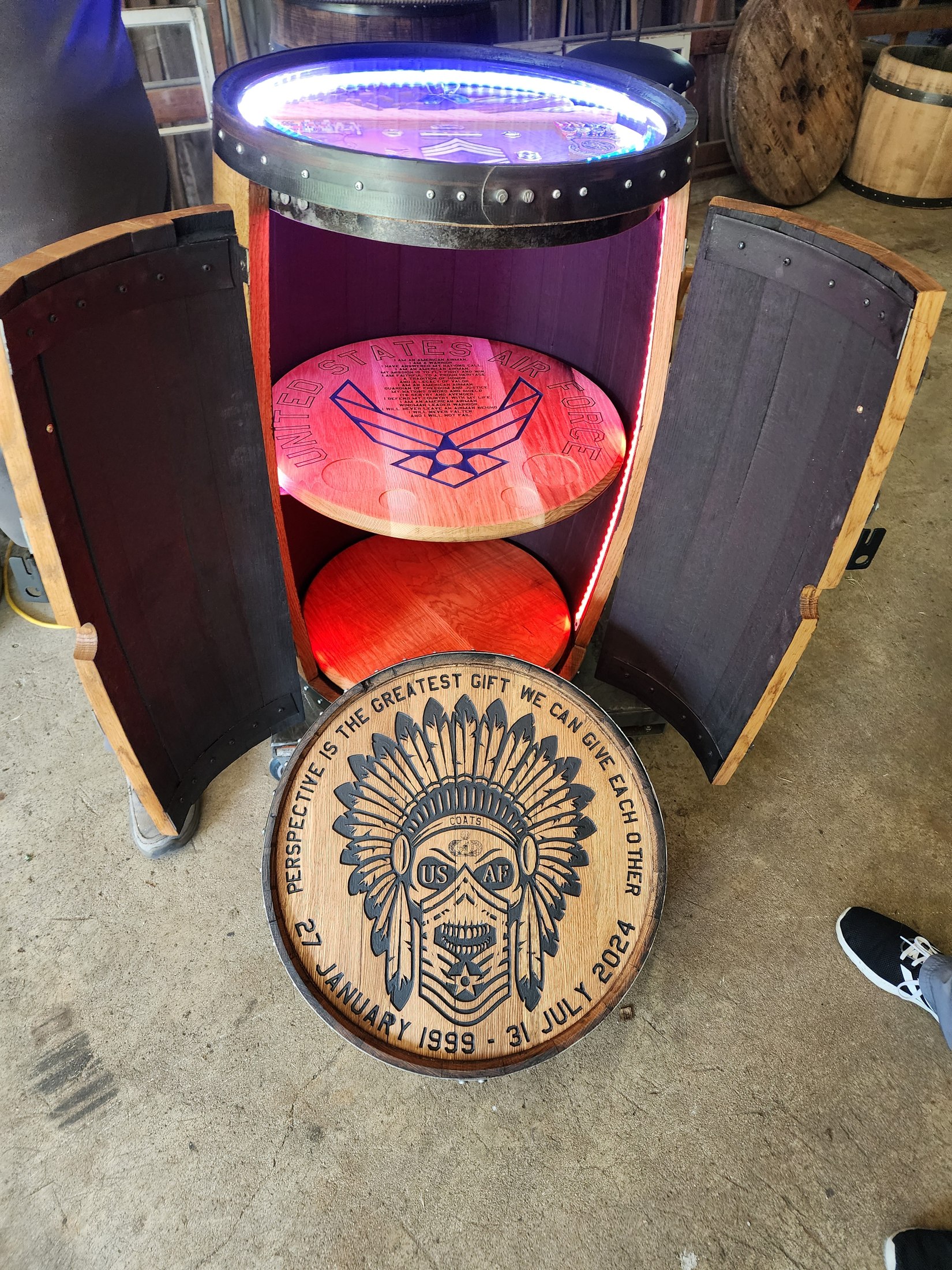 Open barrel cabinet with illuminated Air Force details, an engraved round shelf and a separate retirement cap leaning in front.