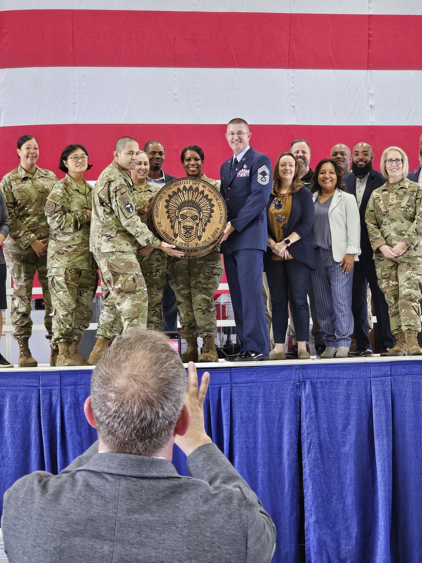 A group at an Air Force retirement gathering with an engraved barrel cap held at the center.