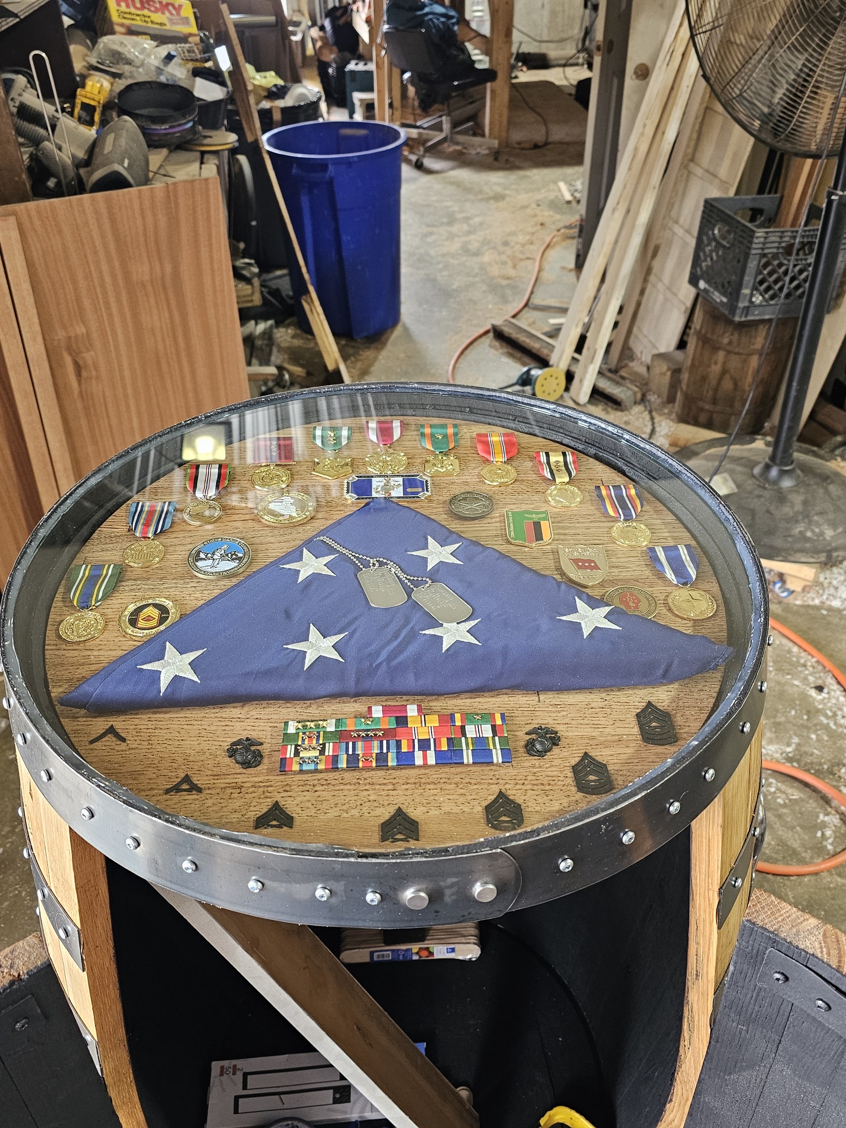 Finished barrel cabinet with a circular military shadow-box top and open curved doors in the workshop.