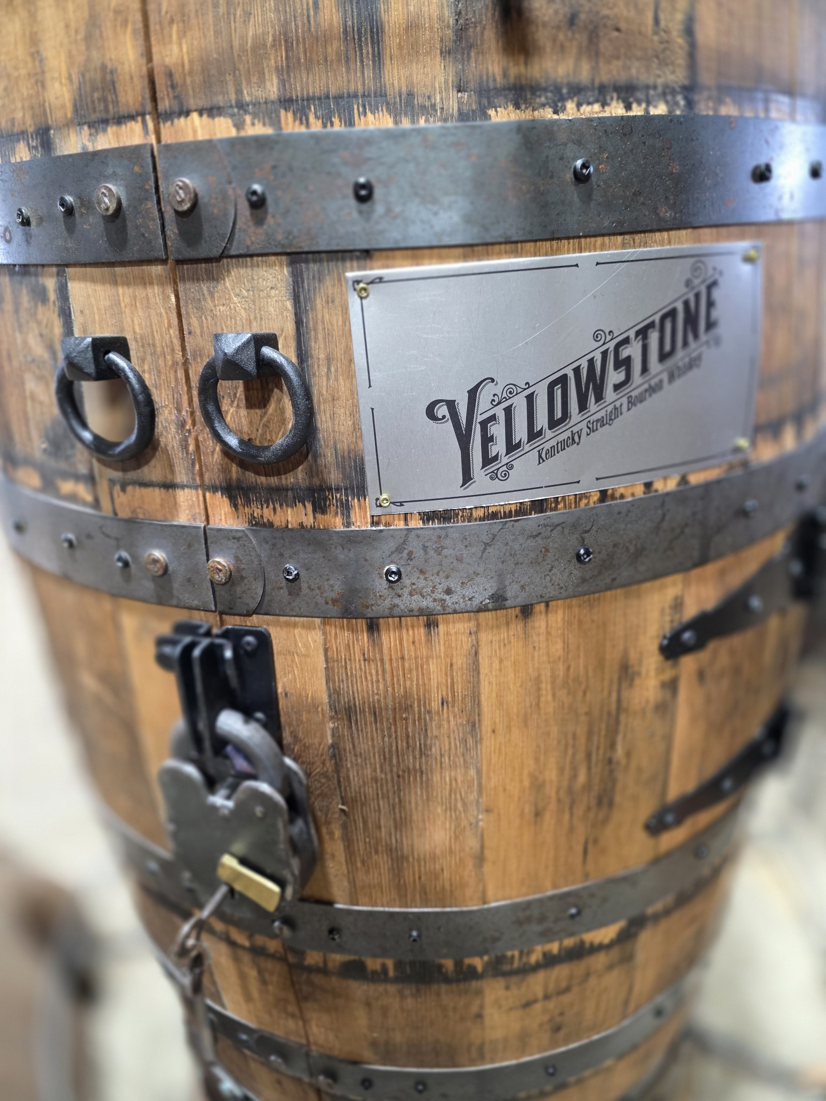 Closed barrel cabinet door with metal hoops, ring handles, a rectangular Yellowstone plaque and a padlock.