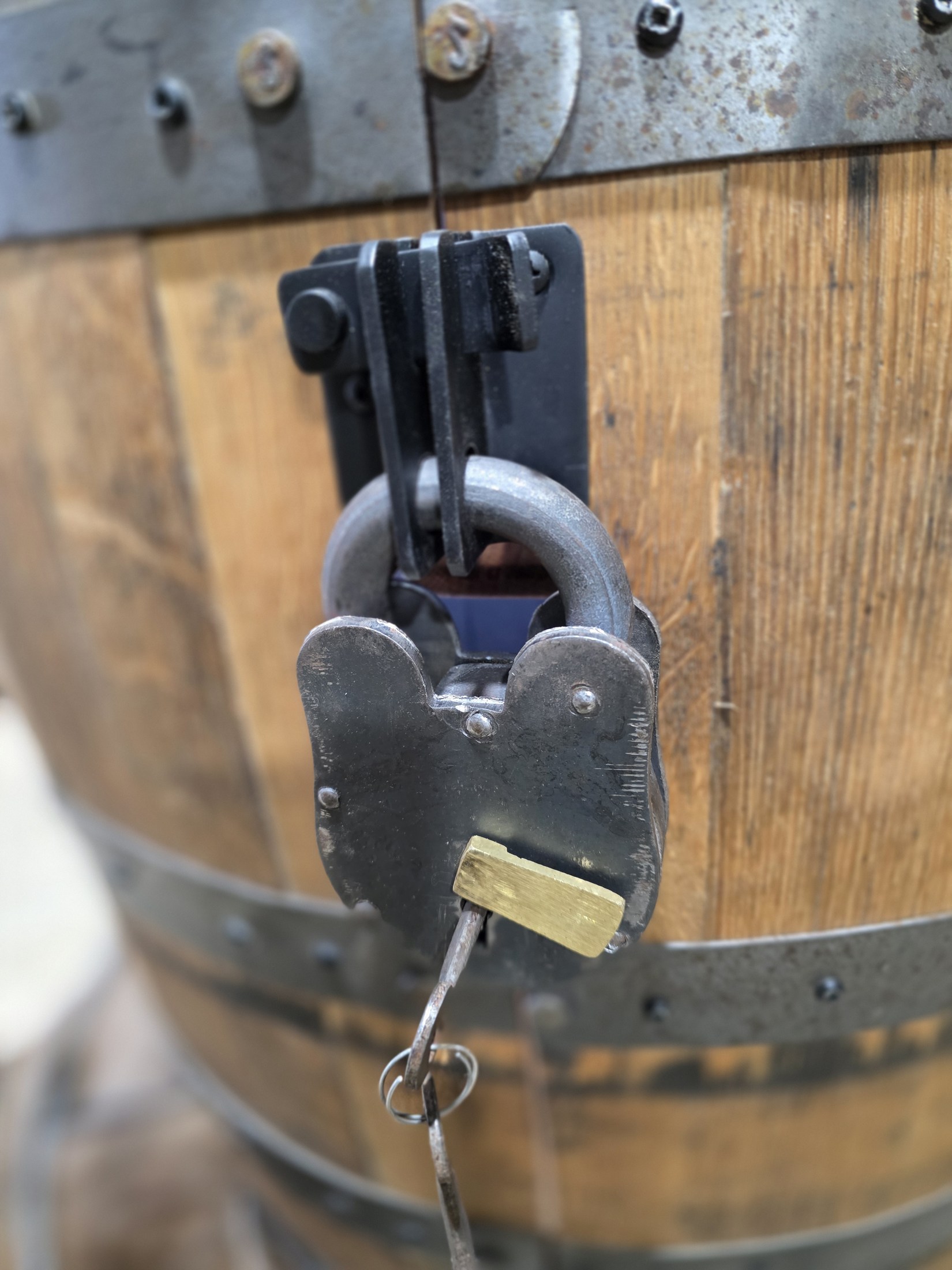 Close view of a hasp and padlock between metal hoops on a barrel cabinet door.
