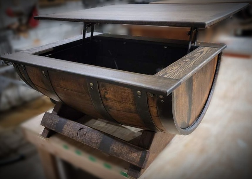Half-barrel coffee table with its rectangular hinged top raised to reveal a storage compartment.