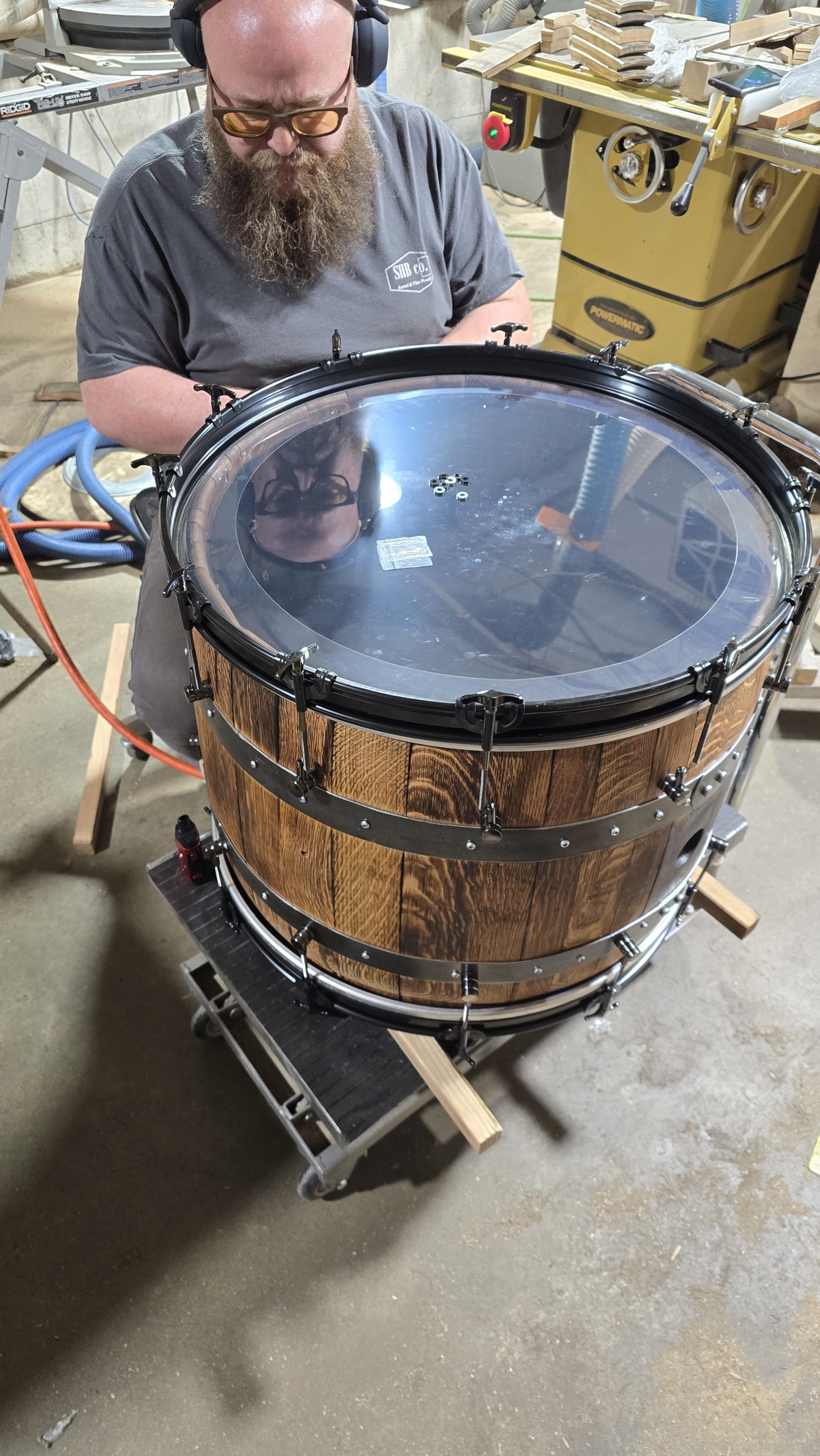 Ryan fitting hardware around a clear drumhead on a barrel shell in the SHB shop.