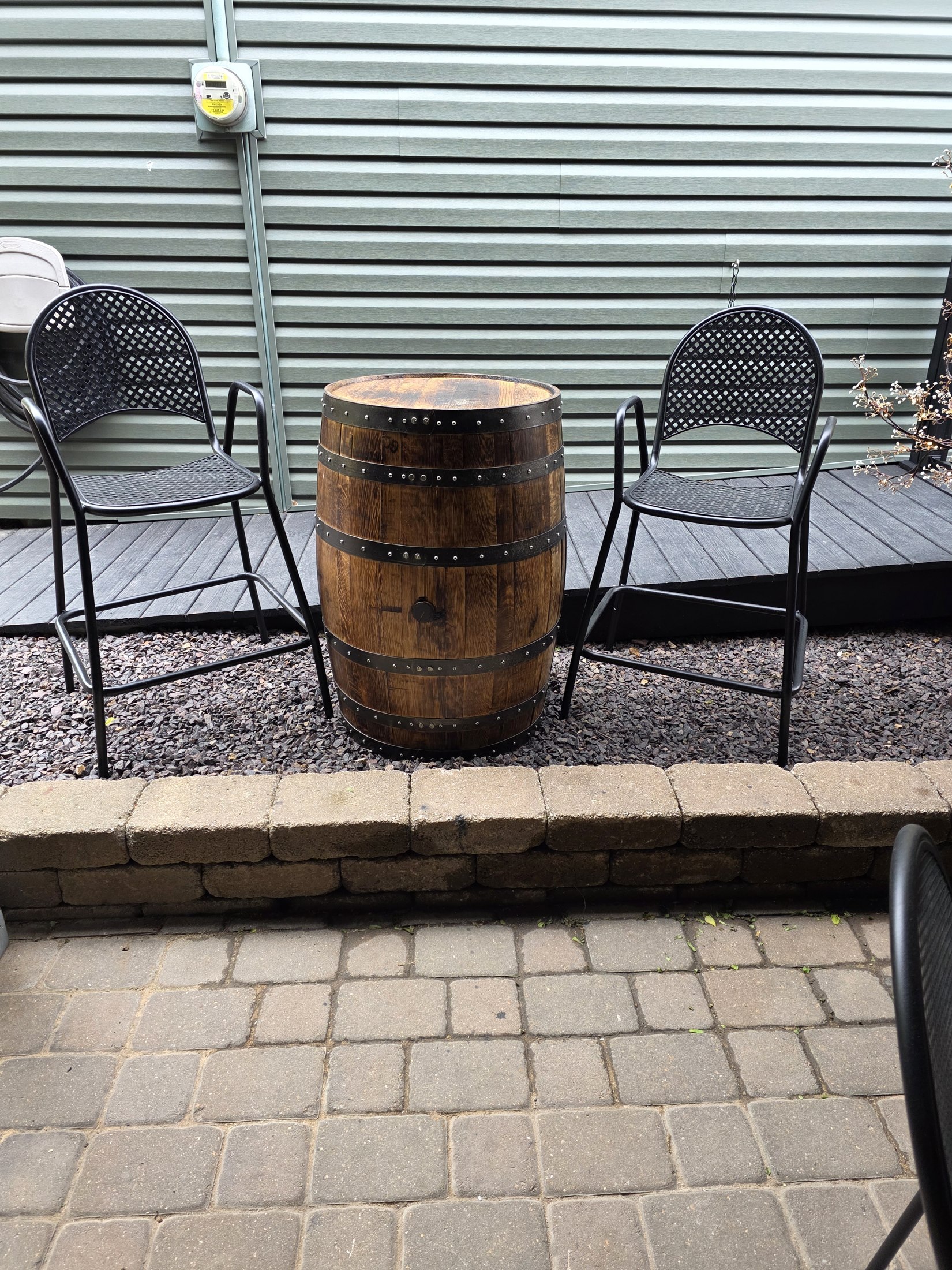 Outdoor table with a round top supported by a barrel, surrounded by chairs at Boarding House Bistro.