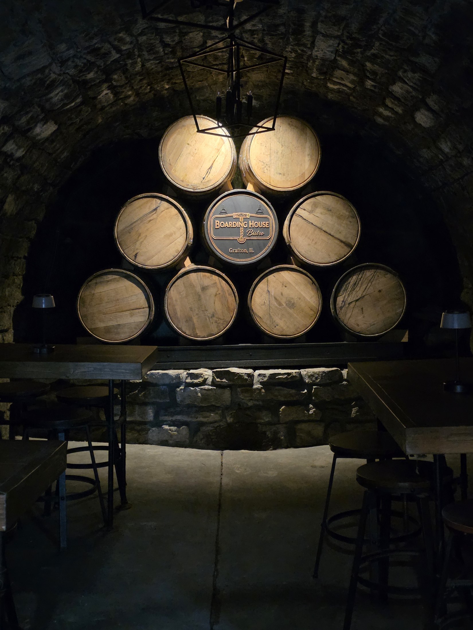 Close view of stacked barrel ends and a central Boarding House Bistro barrel cap inside The Cellar.