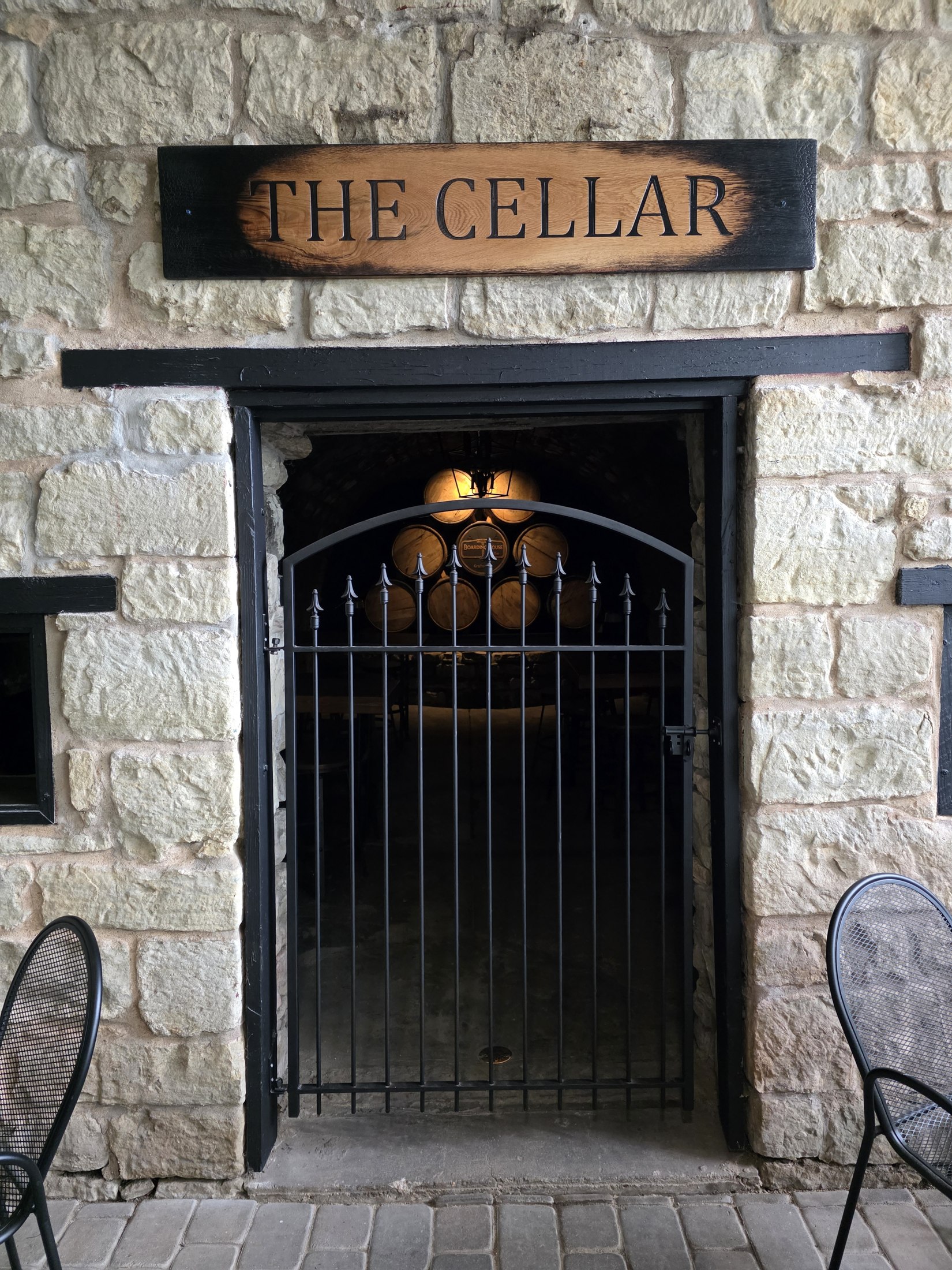Wooden The Cellar sign above a stone-arched entrance at Boarding House Bistro.
