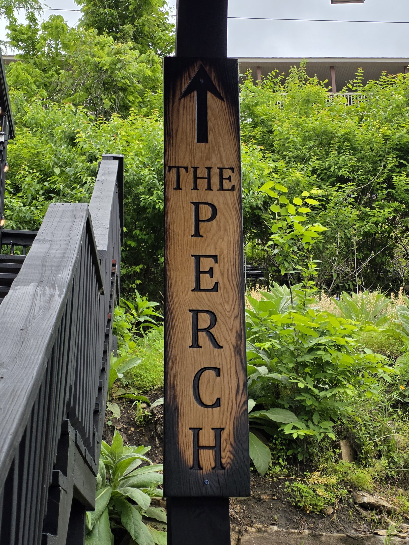 Vertical wooden The Perch sign with an upward arrow.