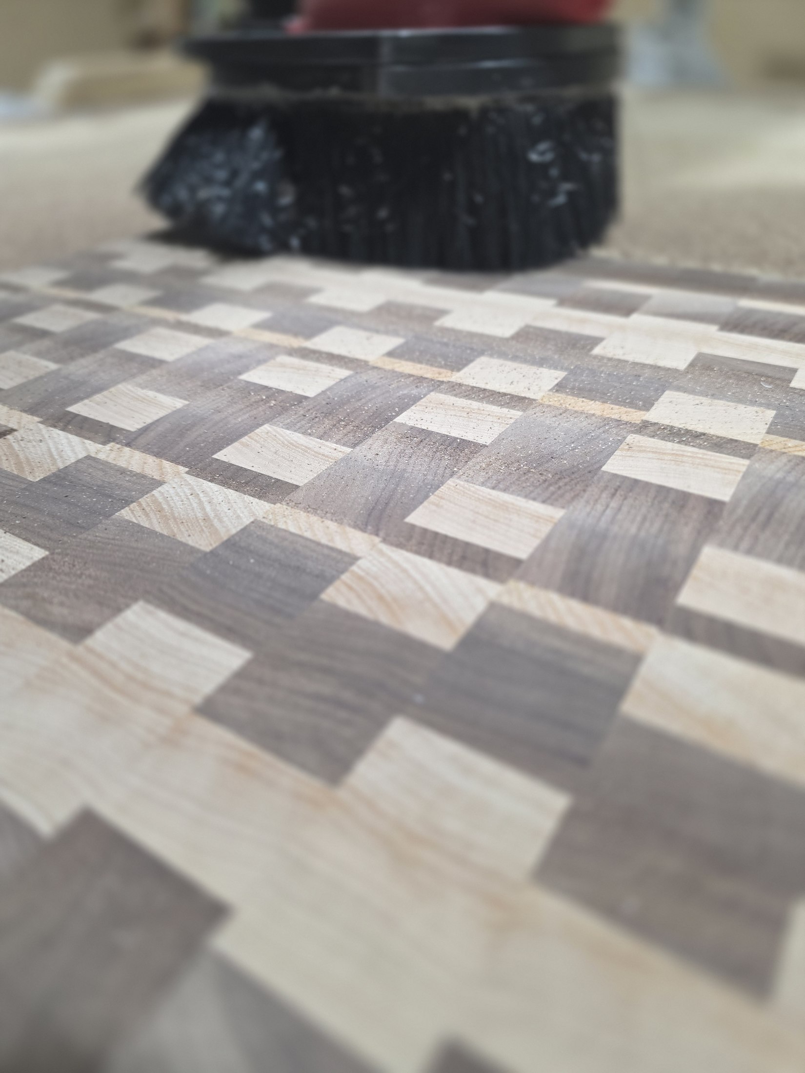 The CNC router positioned over a multi-species patterned wooden panel on the machine bed.