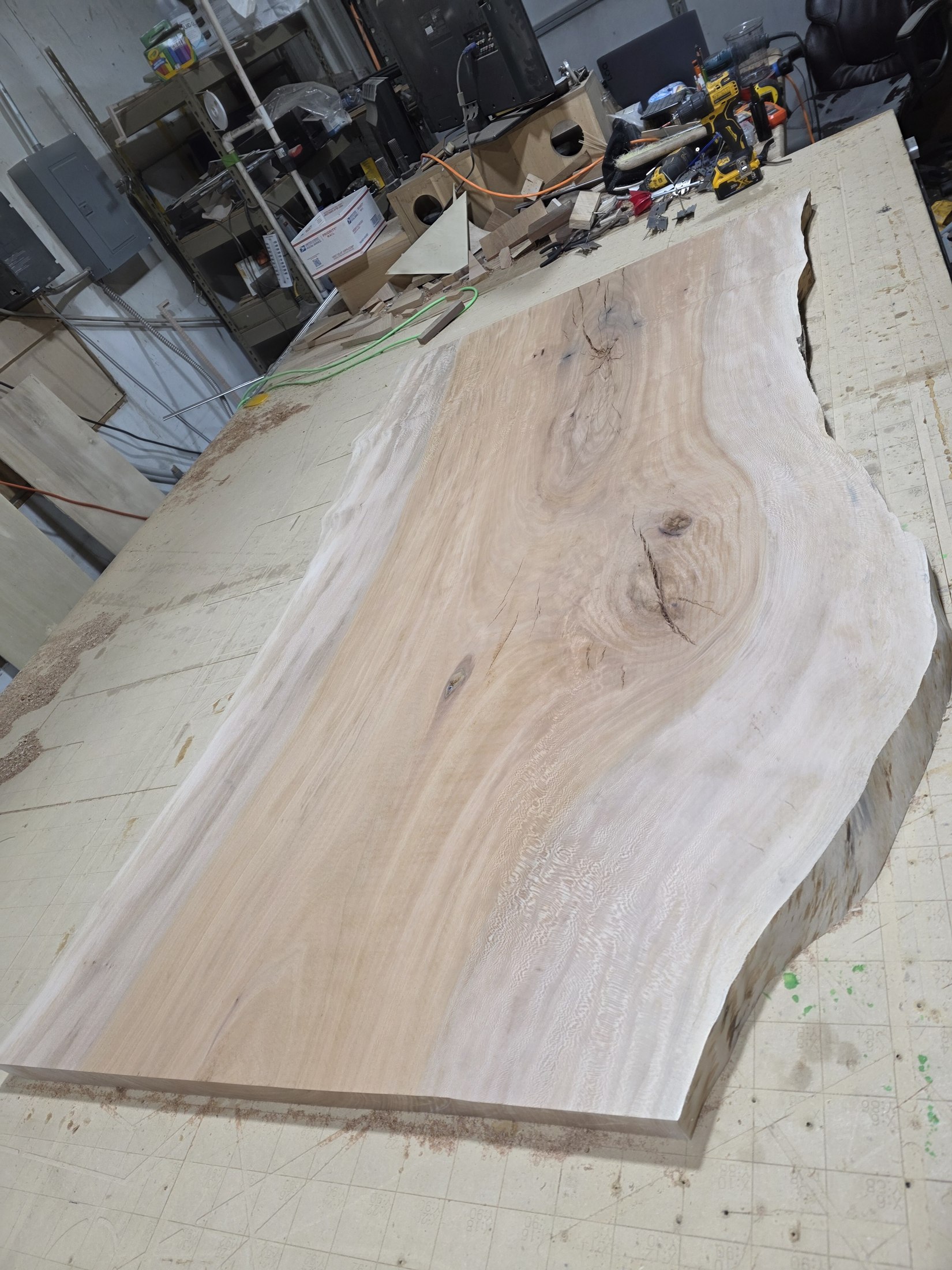 A large live-edge wood slab on the CNC bed during surface preparation.