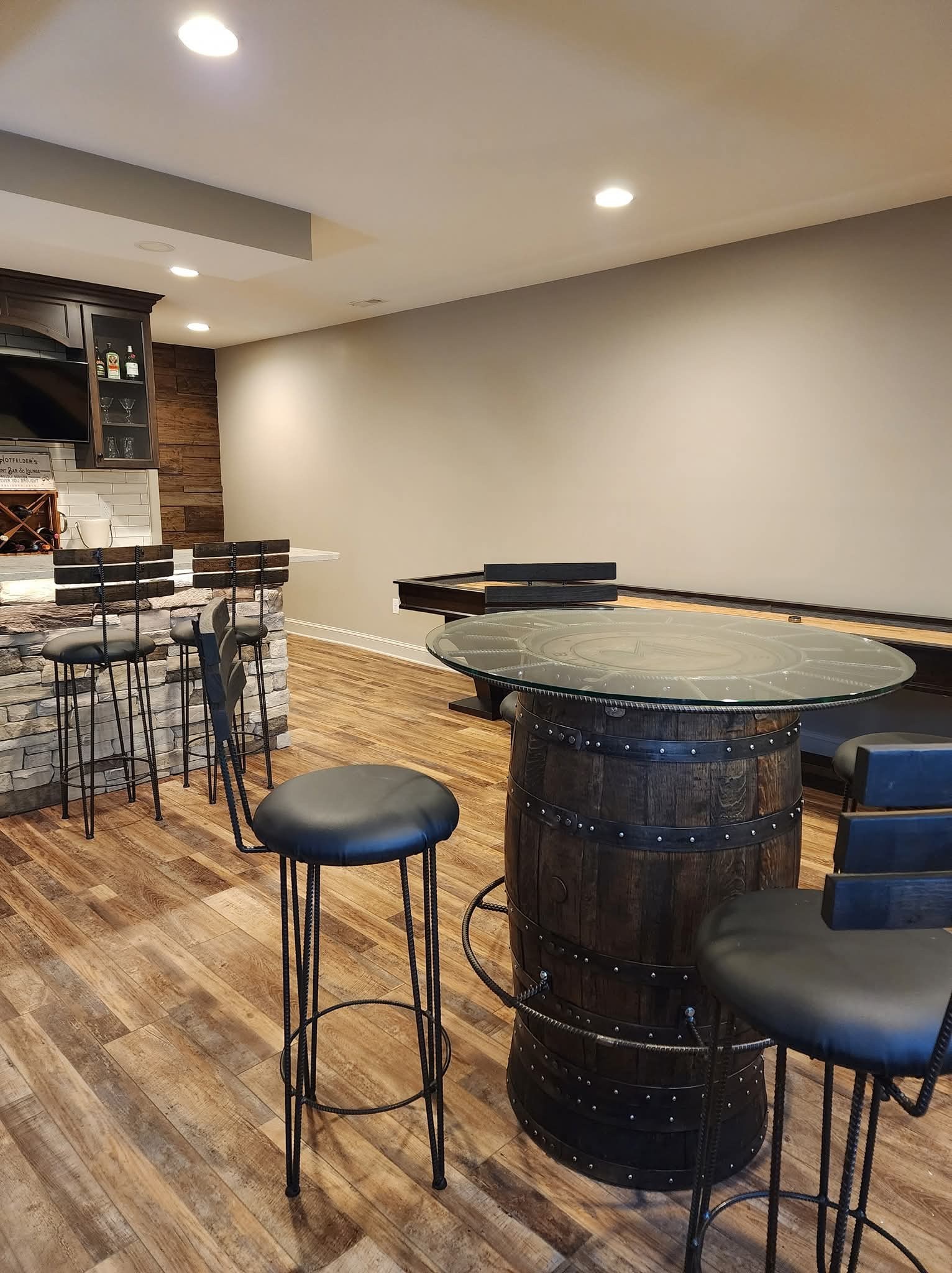 Glass-topped barrel cocktail tables with tall dark stools arranged in a furnished home gathering area.