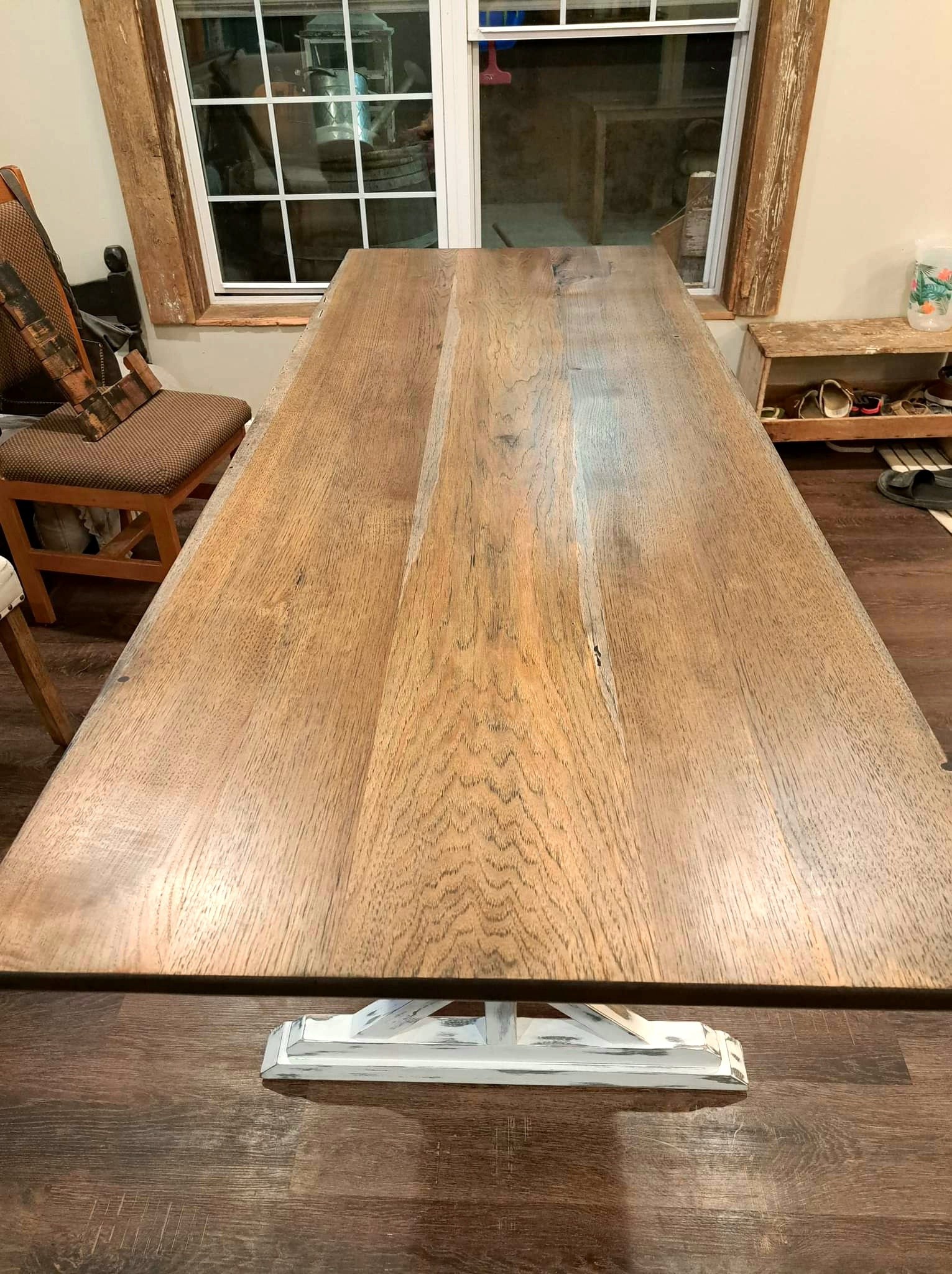 Long wood dining-table top with visible grain and a metal handle centered at the near end.