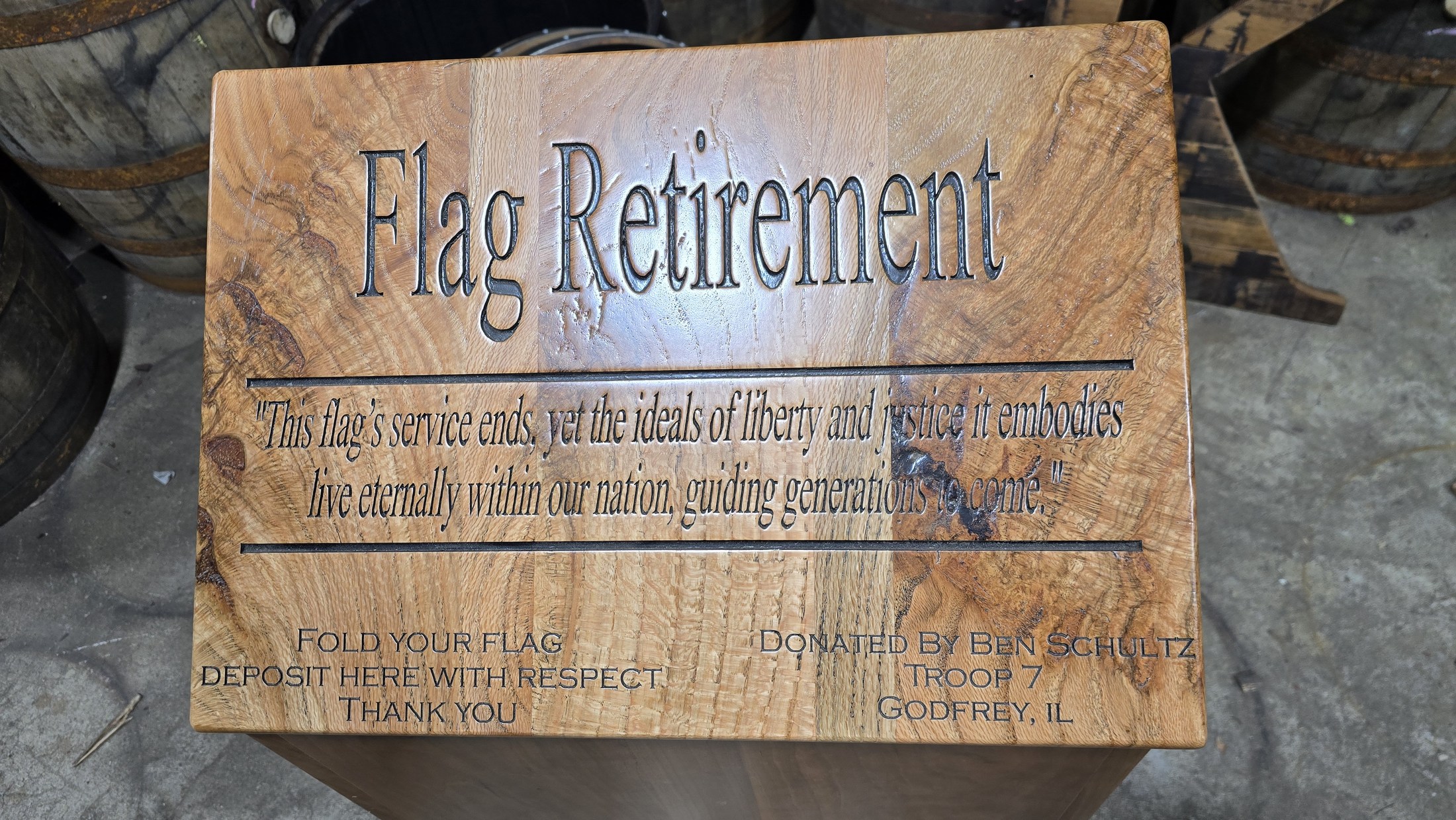 Engraved flag-retirement lid with deposit slot, respectful-use instructions and a dedication to Ben Schultz of Troop 7 in Godfrey.