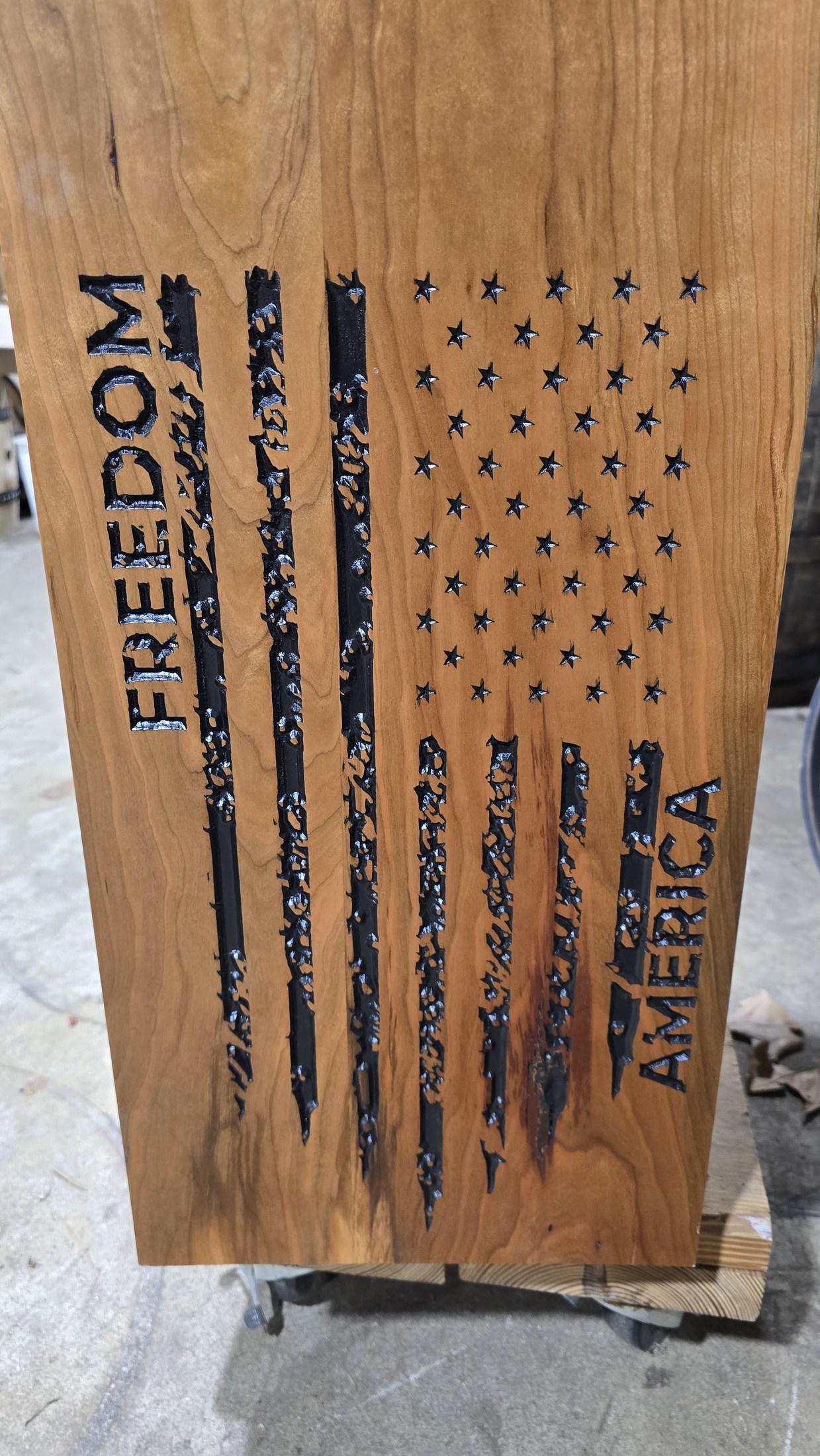 Tall wood panel with a carved American flag and Freedom America lettering on the front of the flag-retirement box.