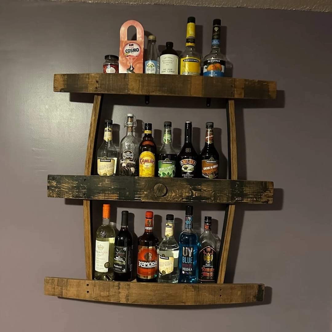Three staggered barrel-stave shelves hold bottles on the wall in the customer’s home.