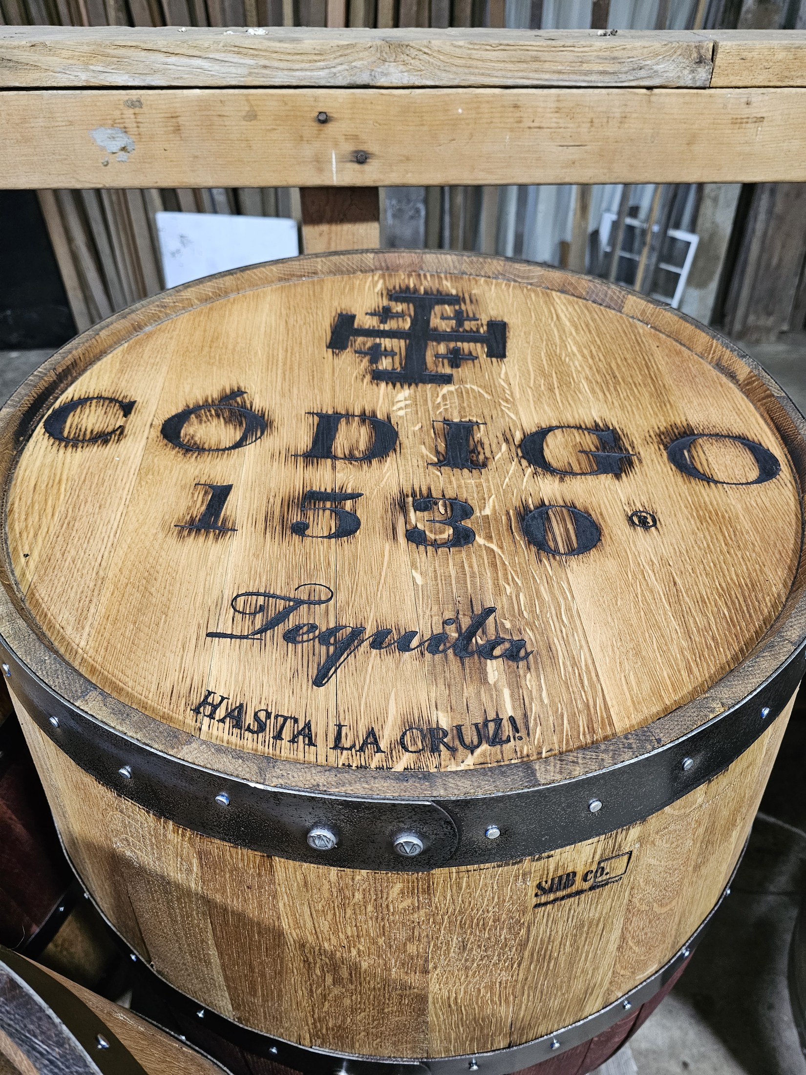 Close view of a barrel cap engraved Código 1530 Tequila and Hasta La Cruz, edged with a metal hoop.