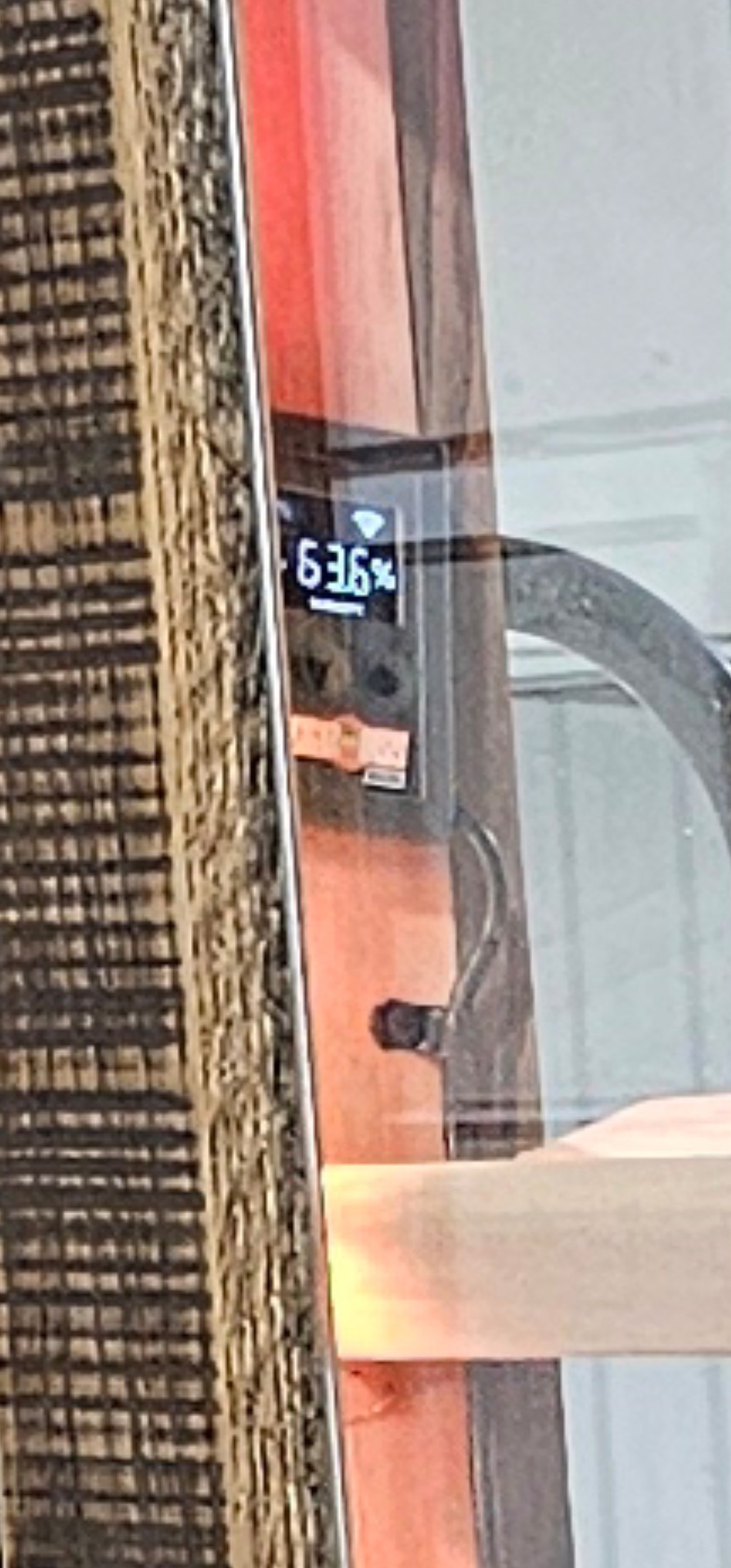 Close view of the humidor’s wood surround, digital display and sliding glass door beside a slatted shelf.