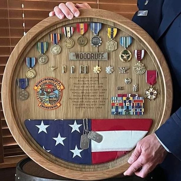 Wooden barrel shadow box with medals, military insignia and an American flag.