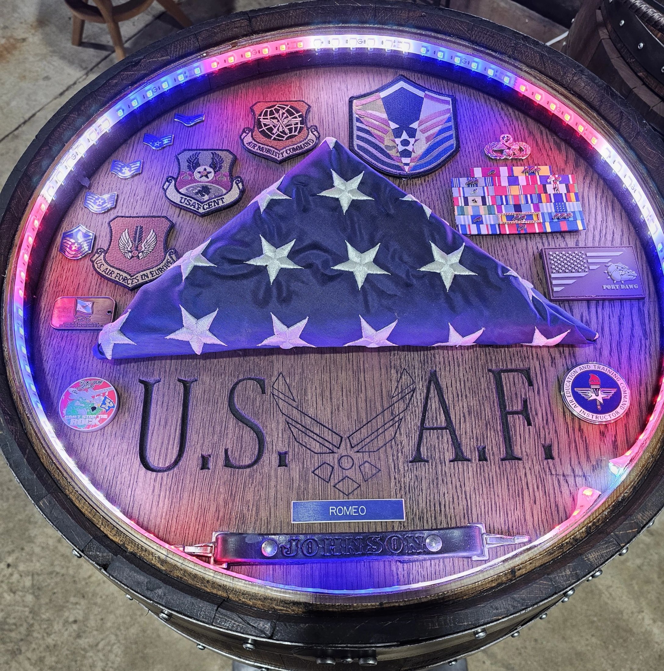 Illuminated Air Force barrel shadow box with a folded flag, patches and medals.
