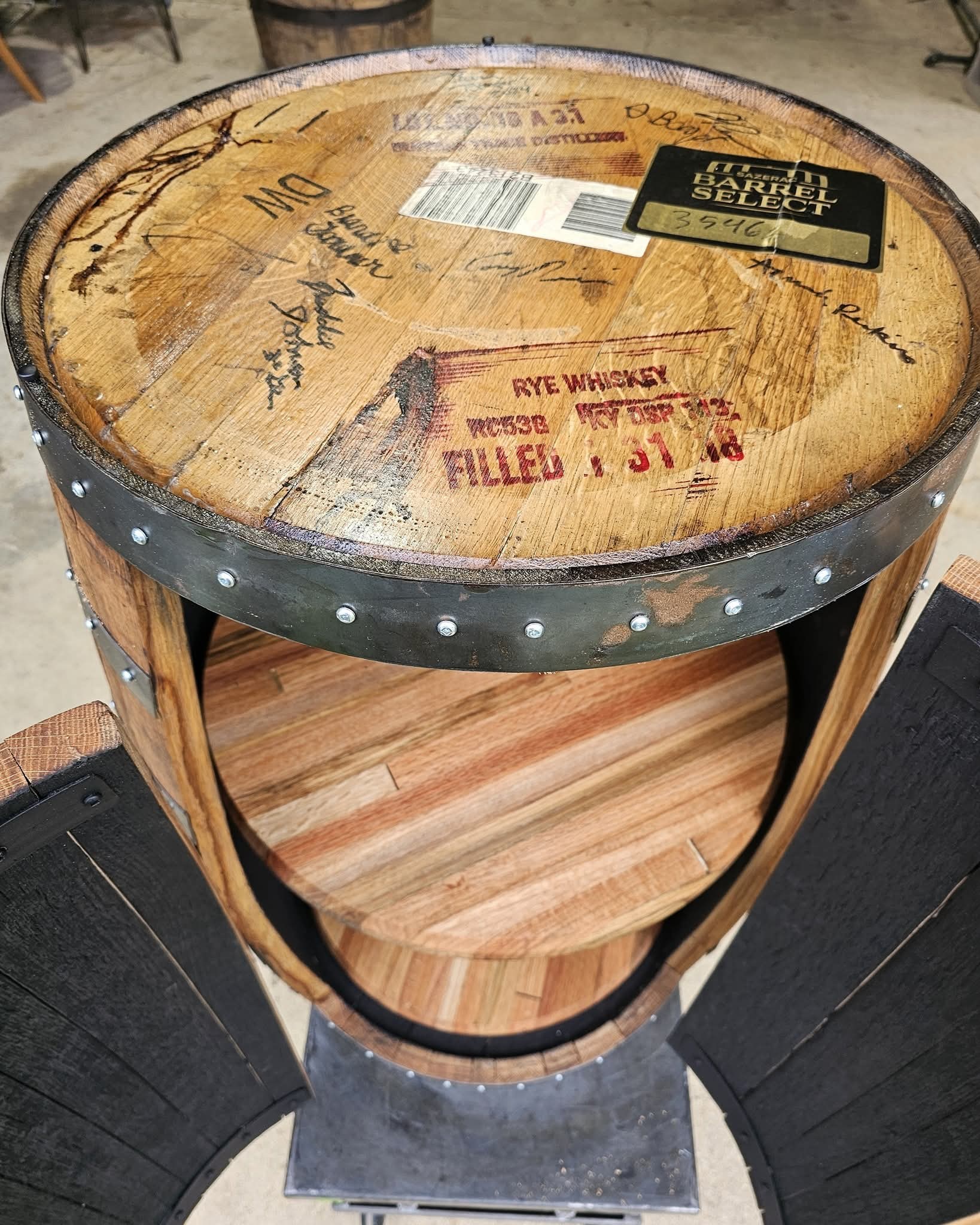 Original signed Buffalo Trace barrel cap above two wood shelves and open curved cabinet doors.