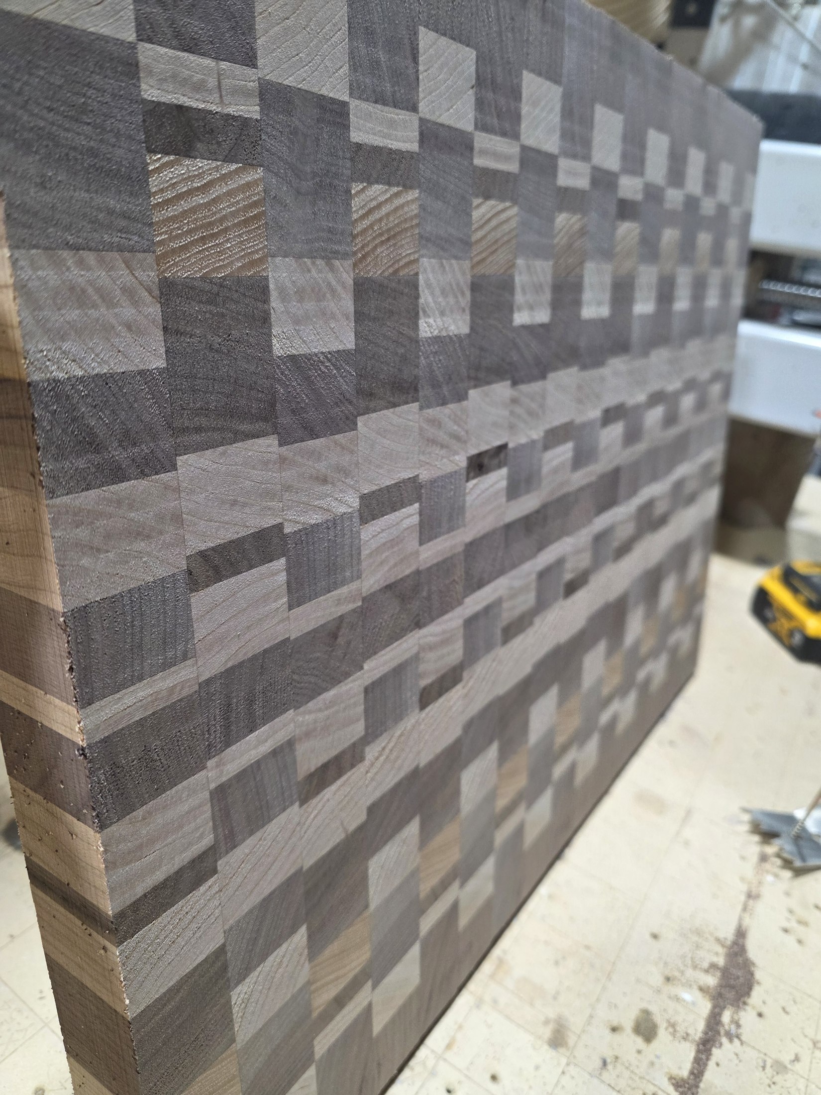 Alternating light and dark wood pieces form a geometric pattern across a flat panel.