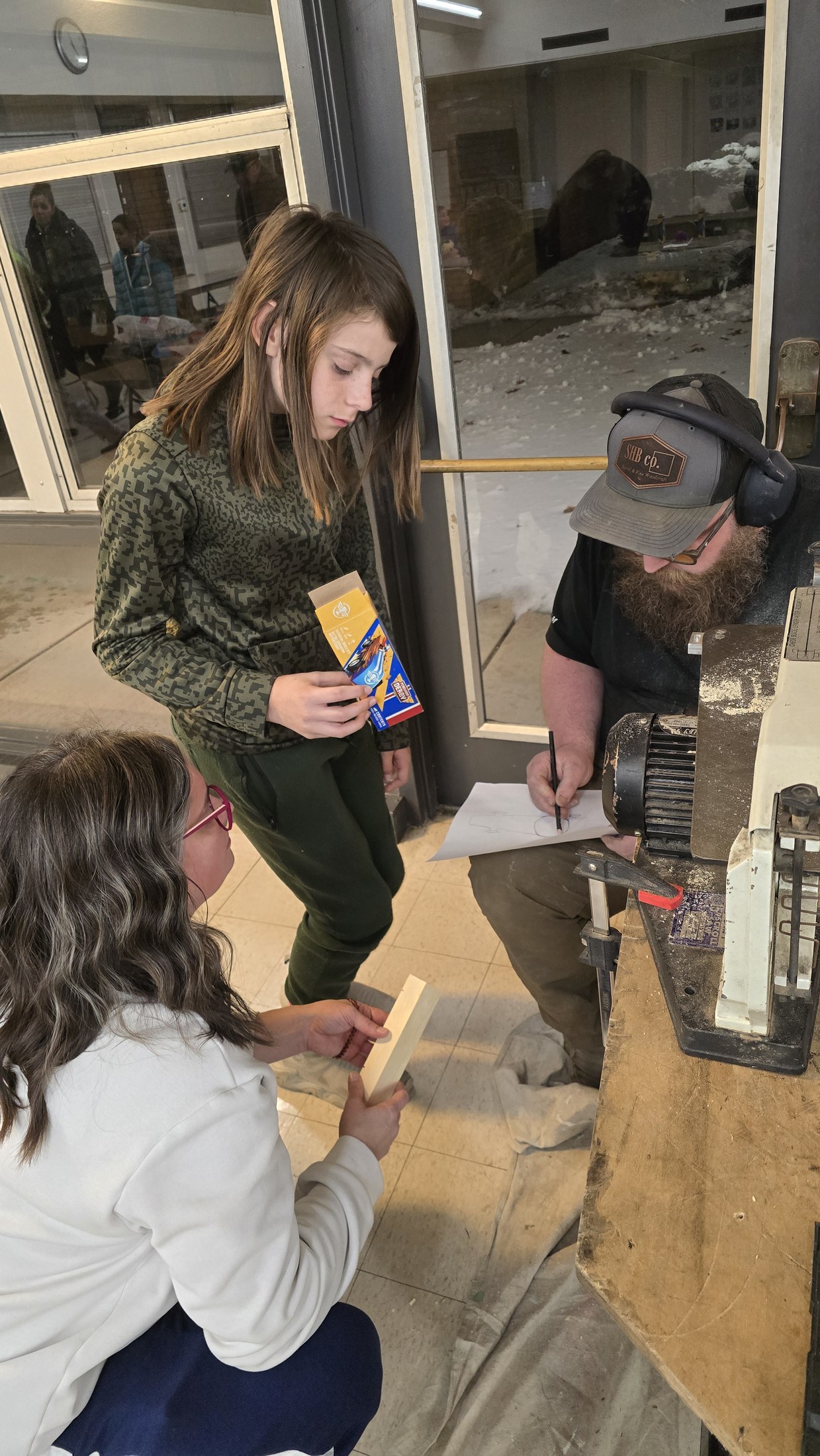 Ryan working at a scroll saw while children watch during the local Cub Scout build night.