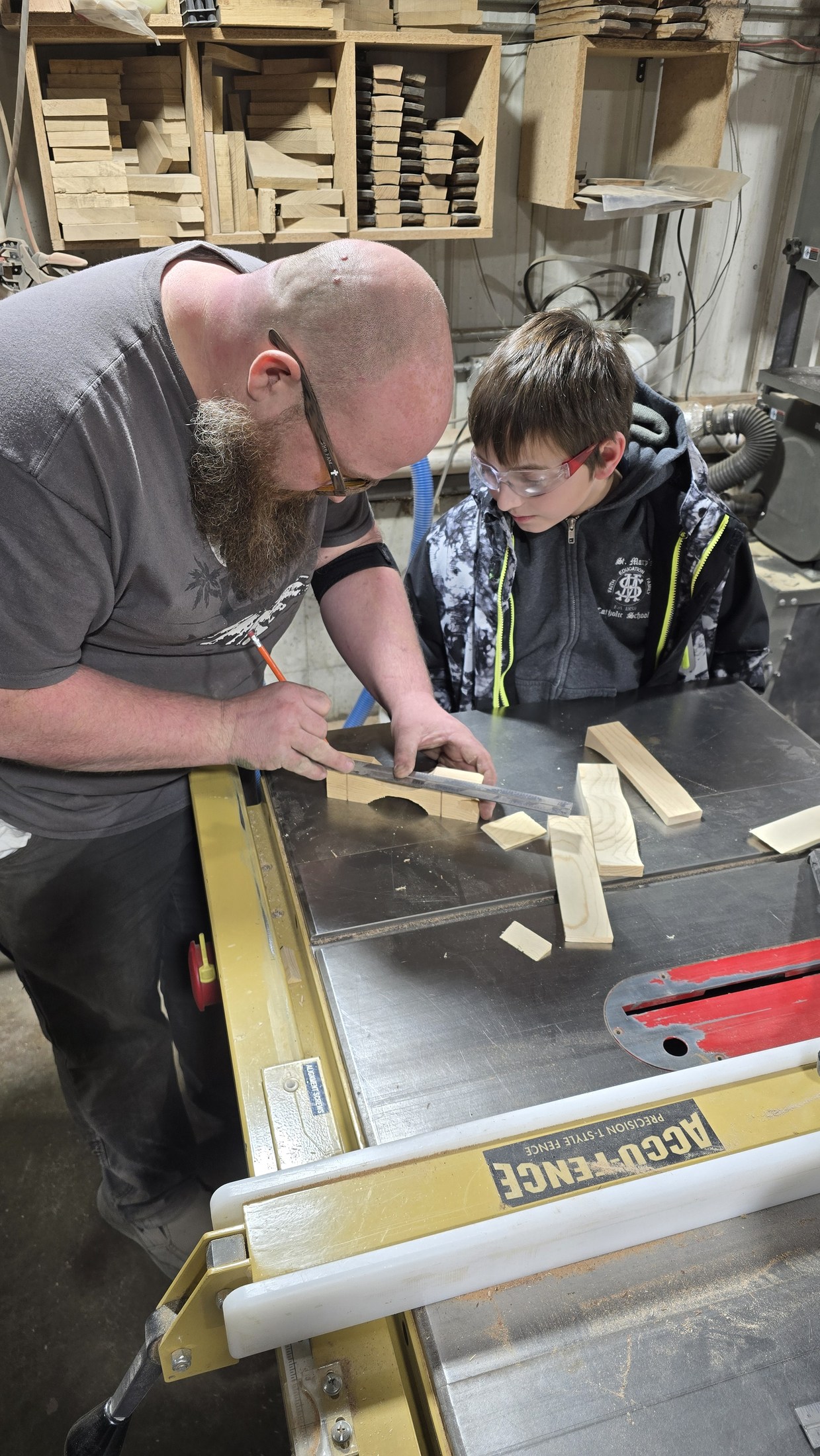 Ryan helping a child mark a Pinewood Derby car blank at the workshop bench.