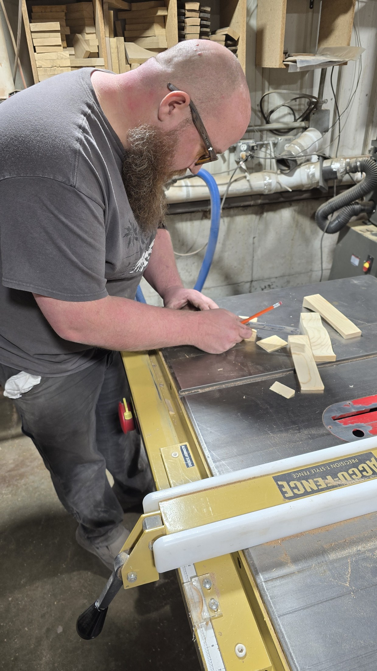 Ryan marking a small pinewood car blank on the shop bench with wood offcuts nearby.