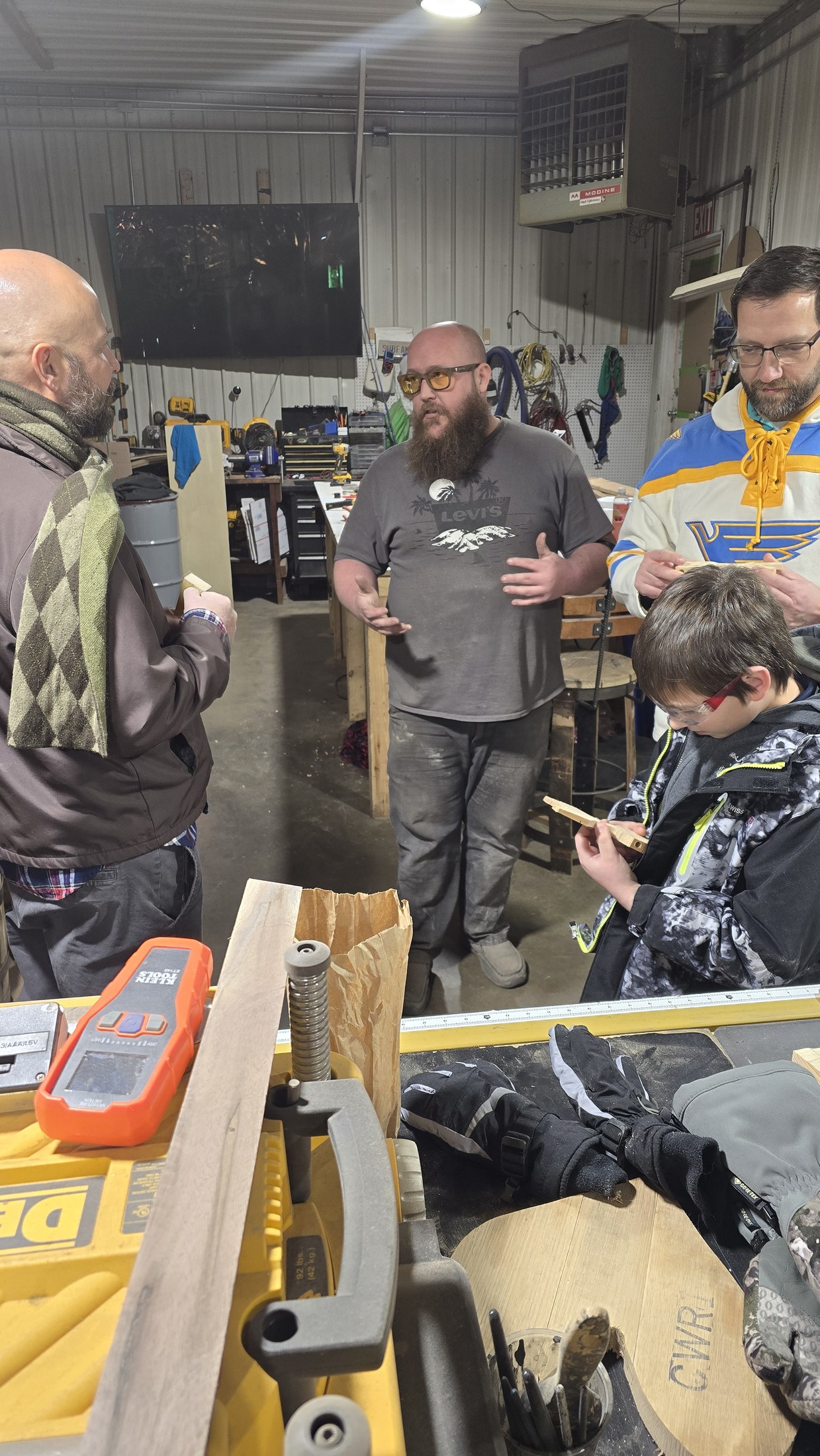 Ryan talking with Cub Scouts and adults gathered around workbenches during a shop build night.