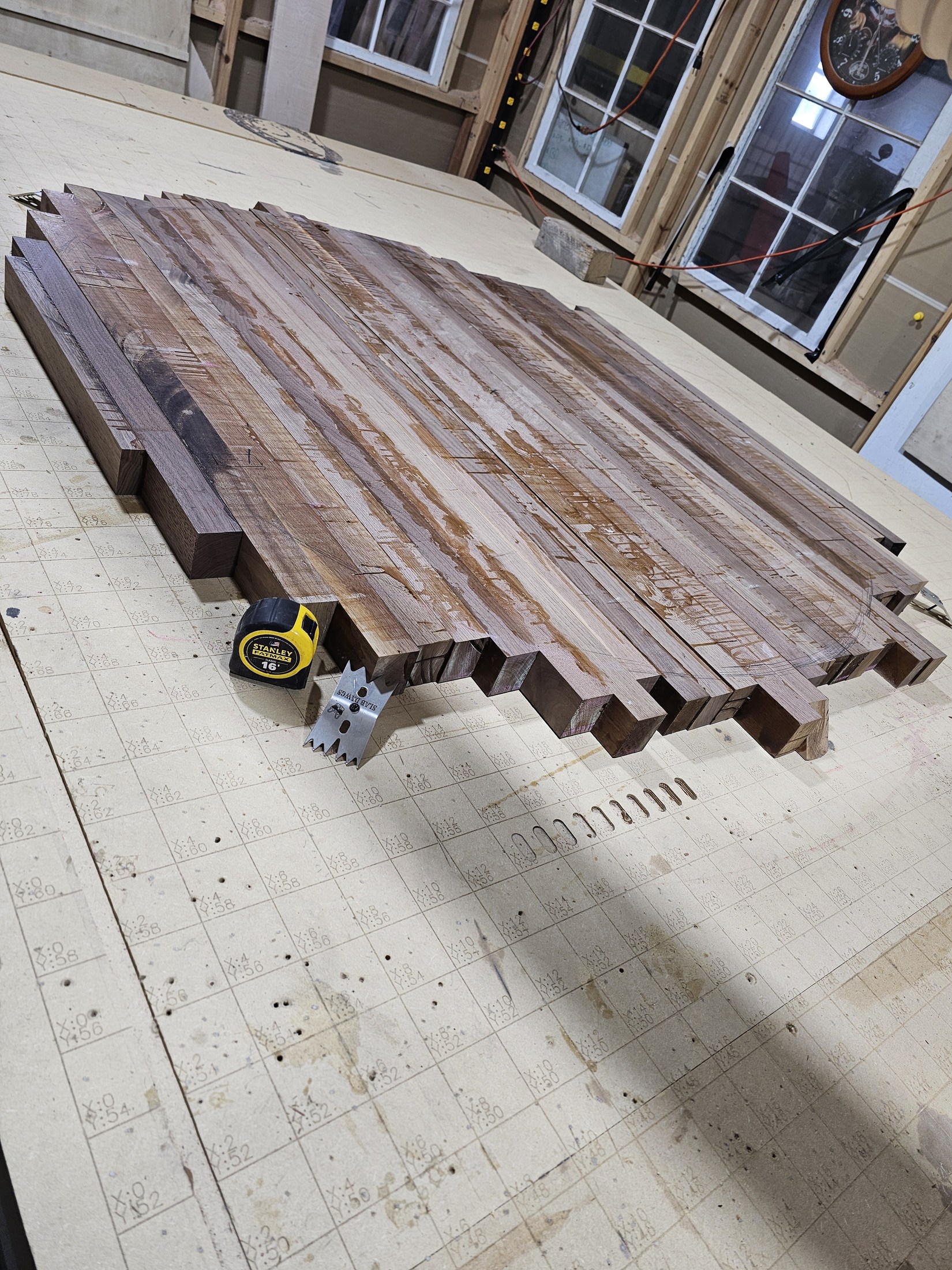 Long wood boards clamped side by side into a wide panel on the workshop floor.