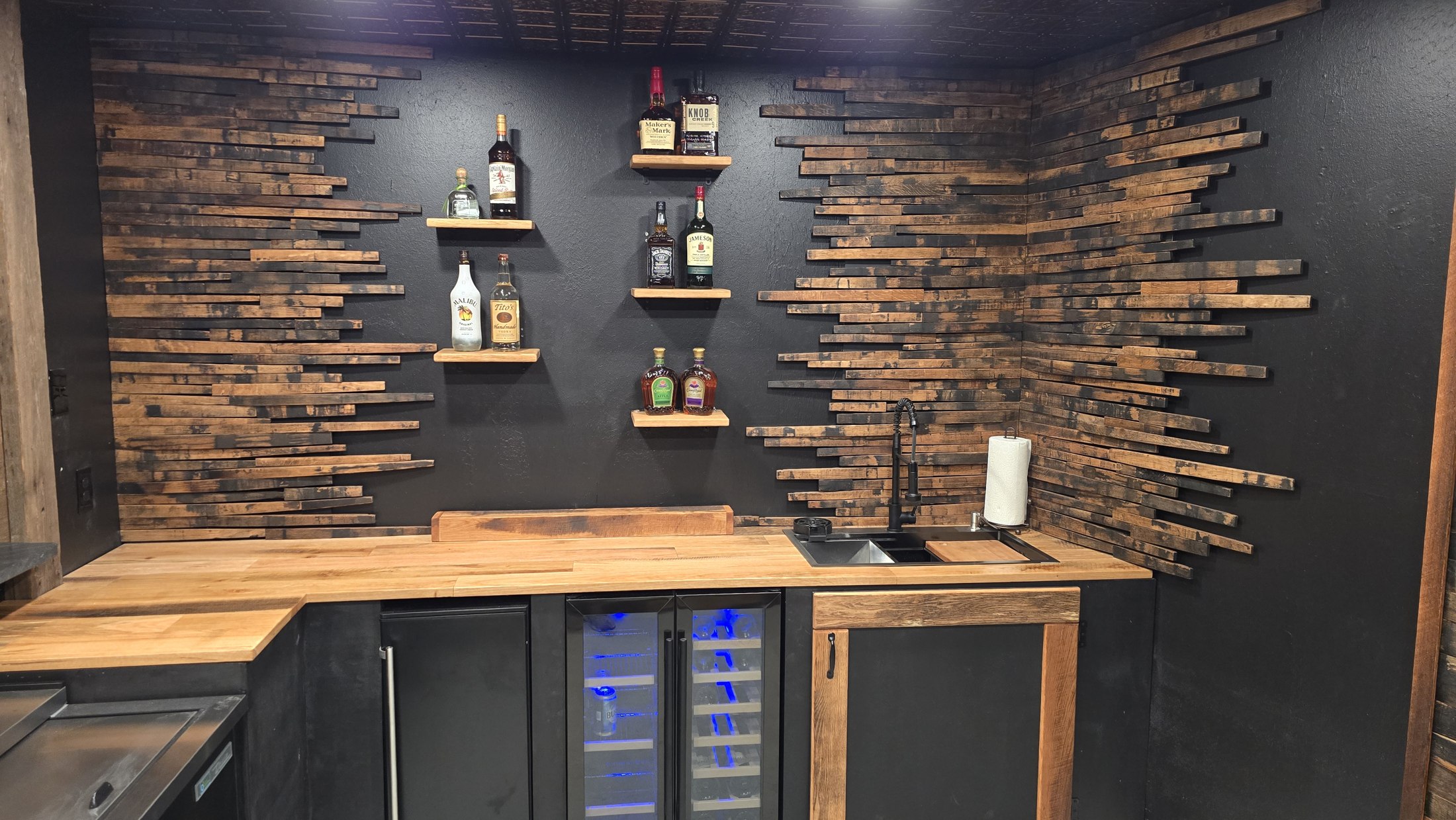 Wide view of Rustic Roots back-bar shelving framed by horizontal wood staves above under-counter coolers.