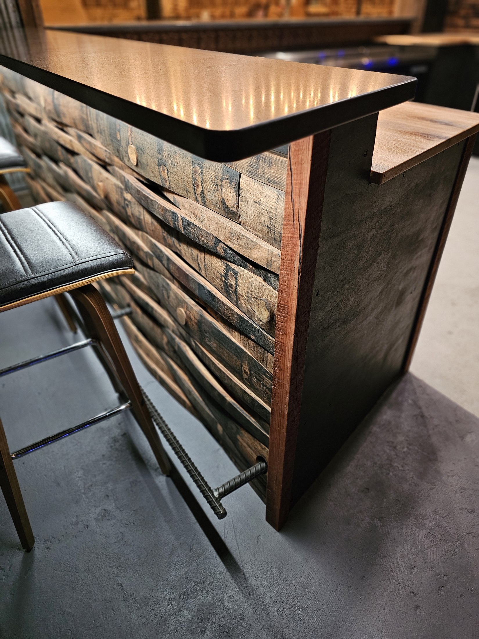Close view of the bar corner, wood stave front and metal foot rail at Rustic Roots.