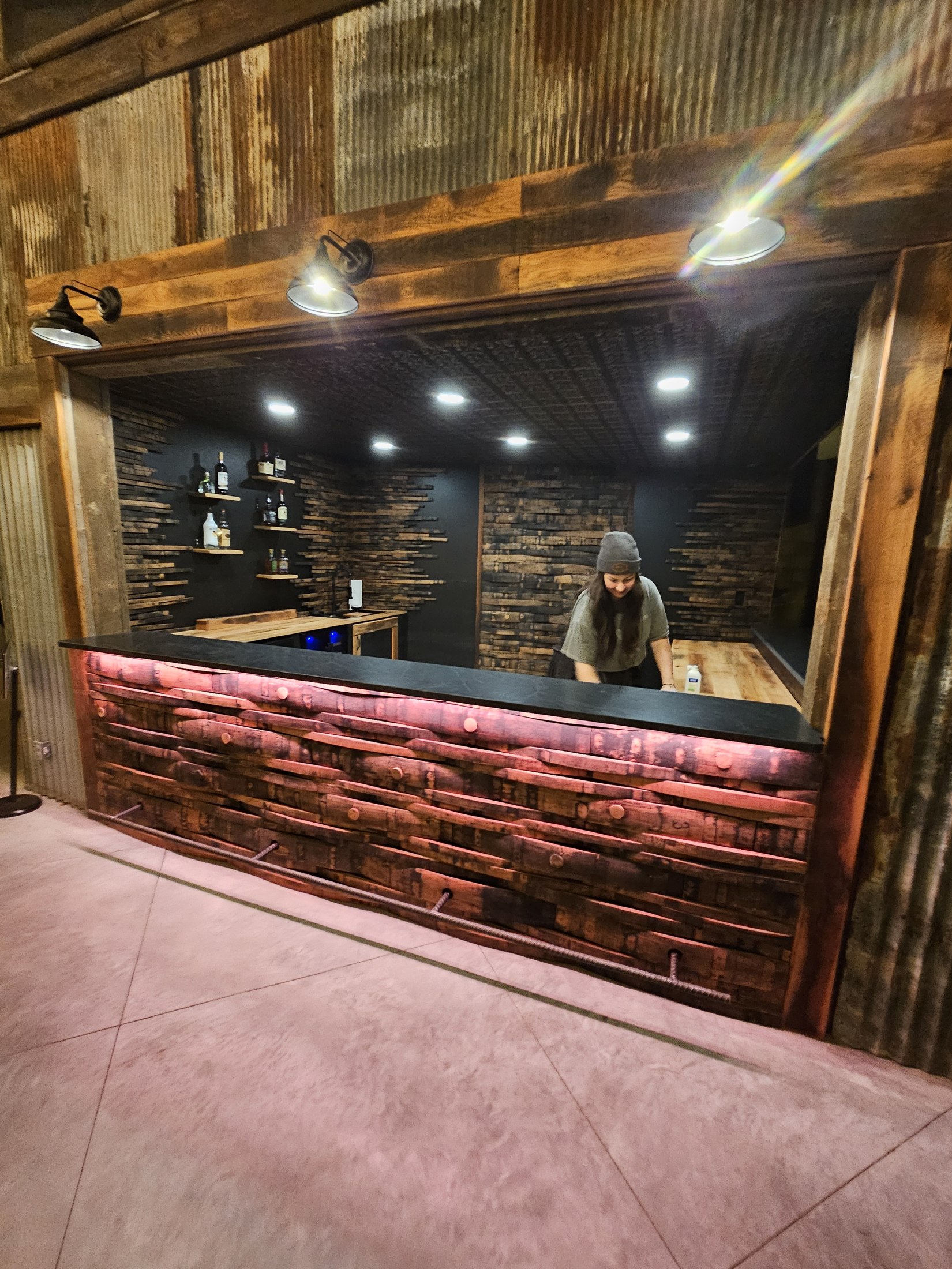 Bar serving opening framed in wood, with the illuminated back bar beyond.