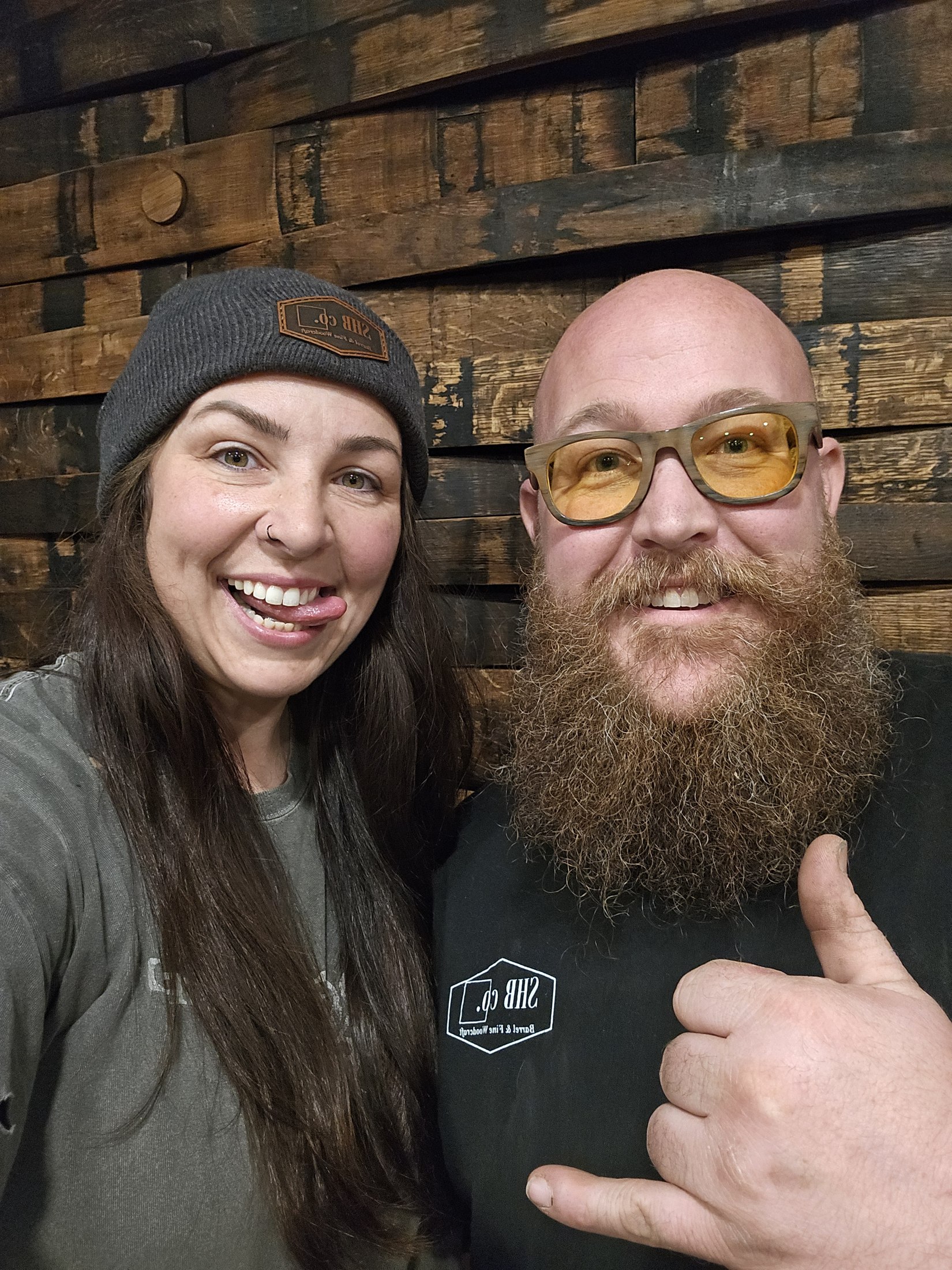 Ryan and Faith standing together in front of the wood-stave bar at Rustic Roots.
