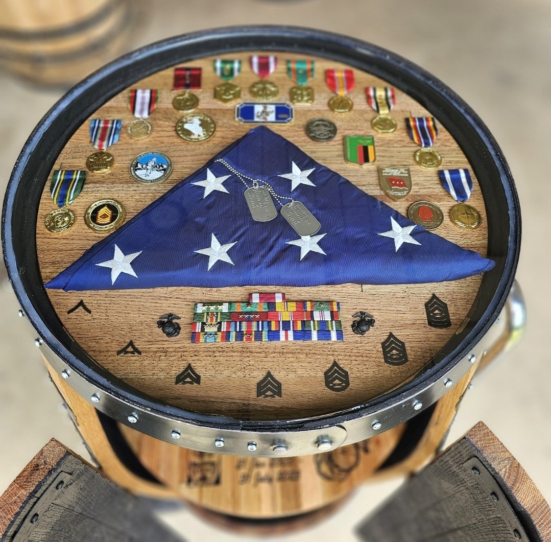 Barrel-top recognition table displaying a folded flag and military keepsakes.