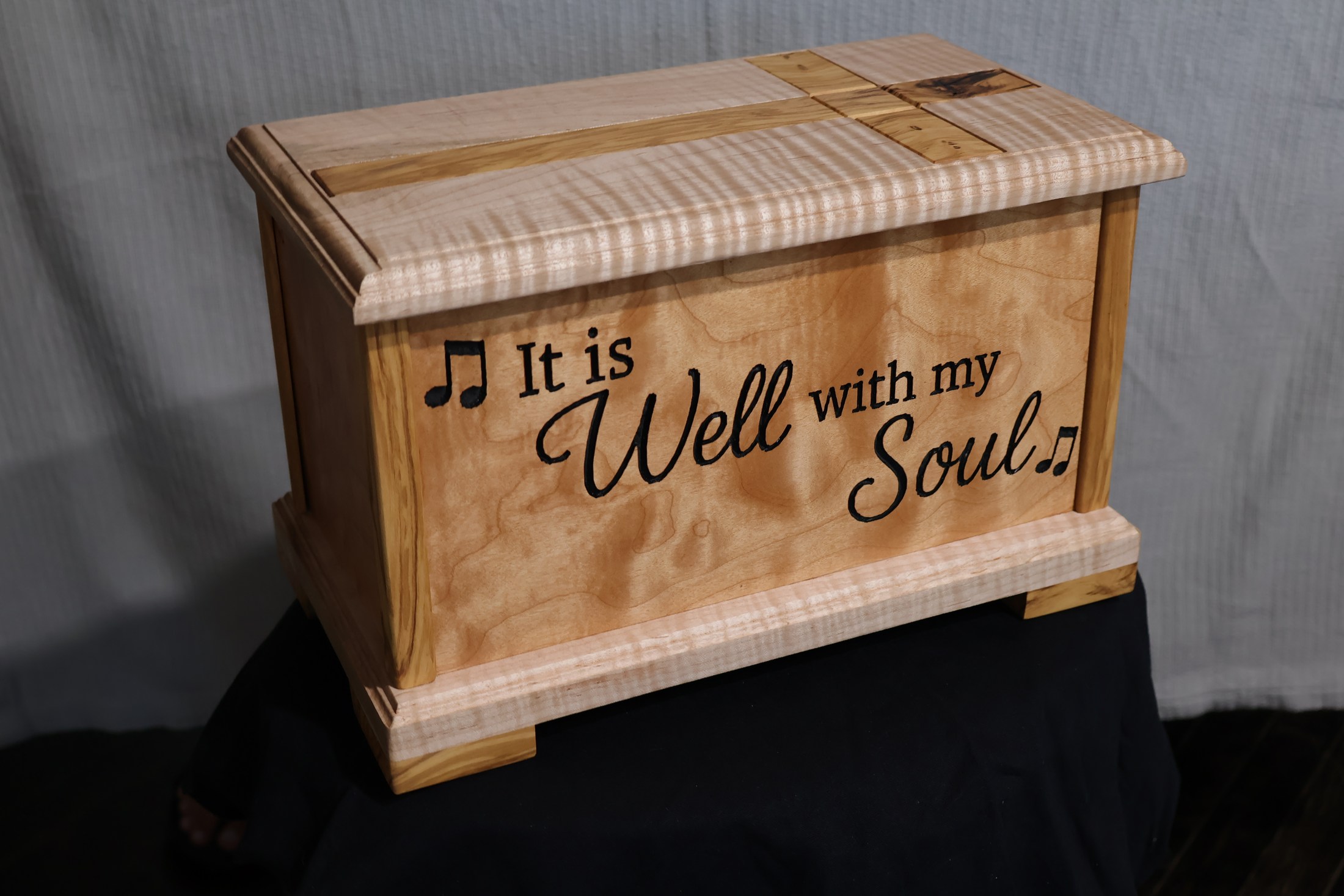 Side of the memorial box engraved It is Well with my Soul, framed by figured wood trim.