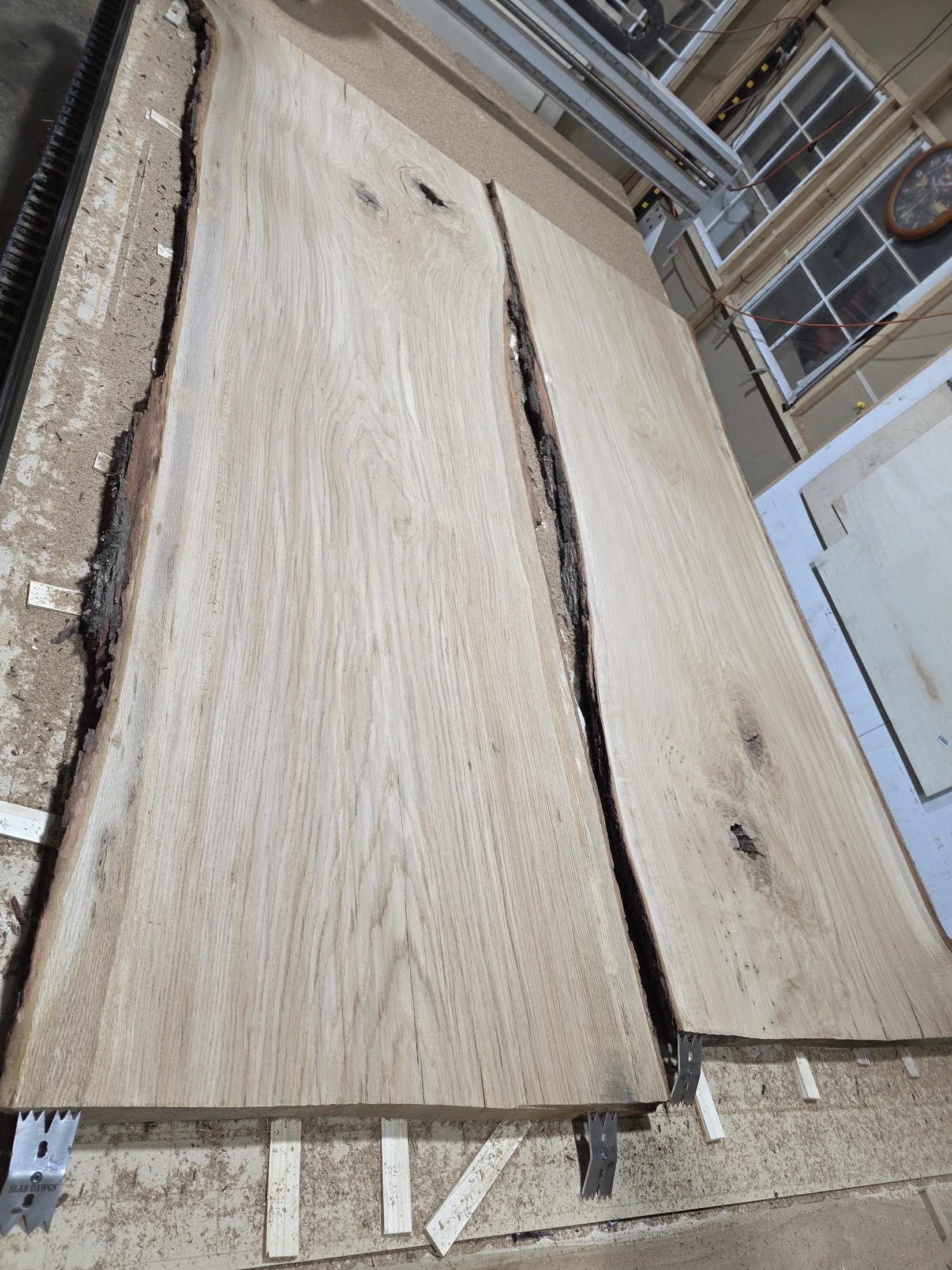 The same live-edge slab sections after surfacing, with pale grain exposed and the natural central opening retained.