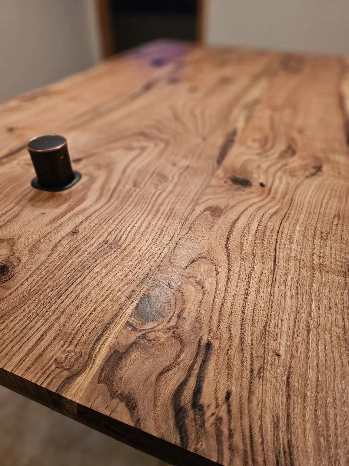 Raised black power outlet set into the figured wood top of the Smith Family island.