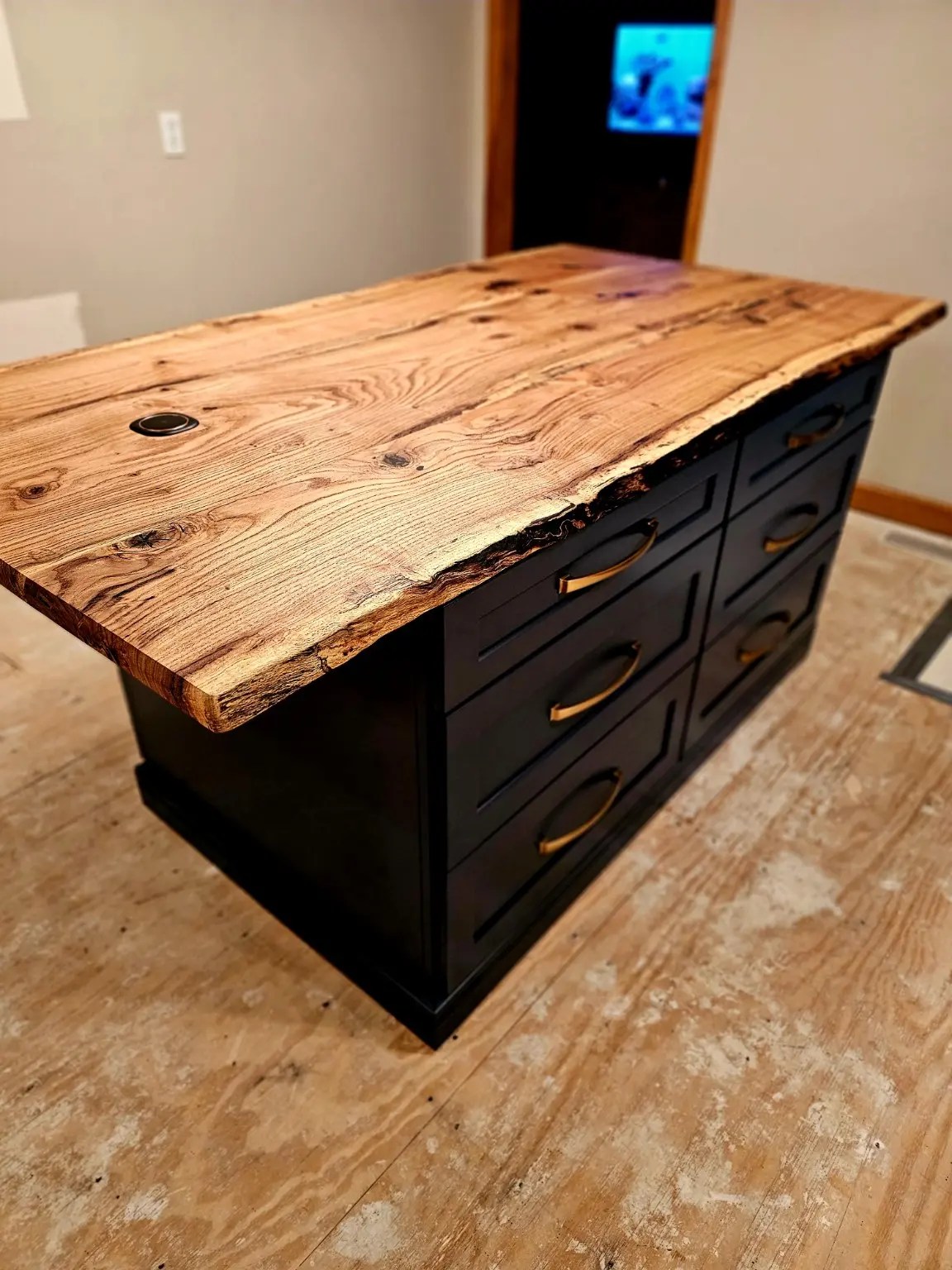 Live-edge black-oak island top over navy cabinets with brass drawer pulls in the Smith family kitchen.