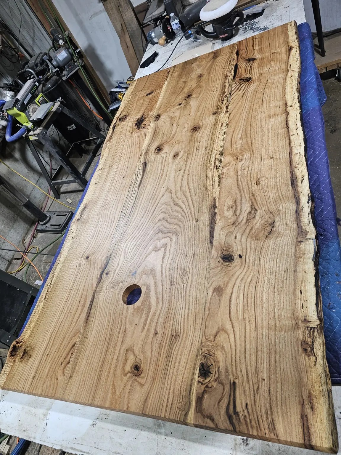 Wide joined live-edge wood top laid out on the workshop bench during fabrication.