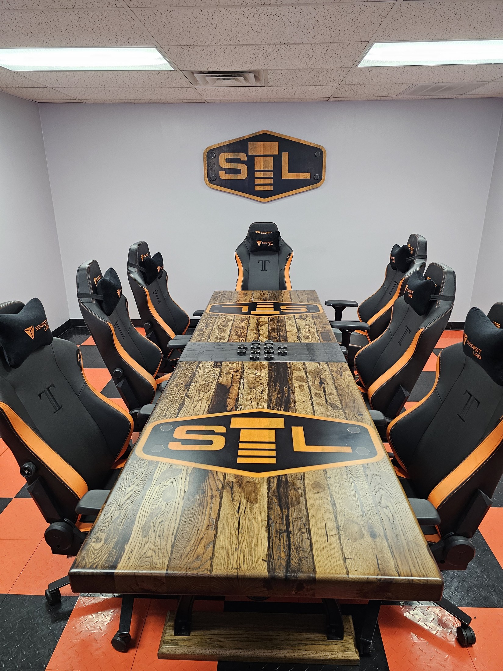 Full-length custom conference table with inset STL emblems, a central display of bolt heads and a matching wall sign in the meeting room.