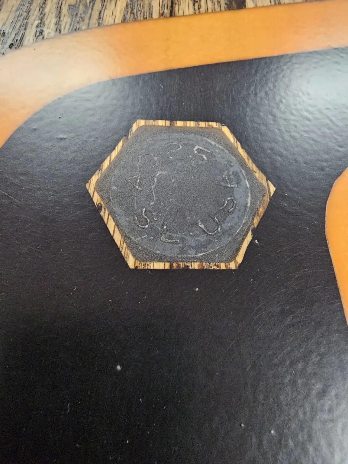 Close view of a large hexagonal bolt head incorporated into a black and gold STL-branded wooden feature.