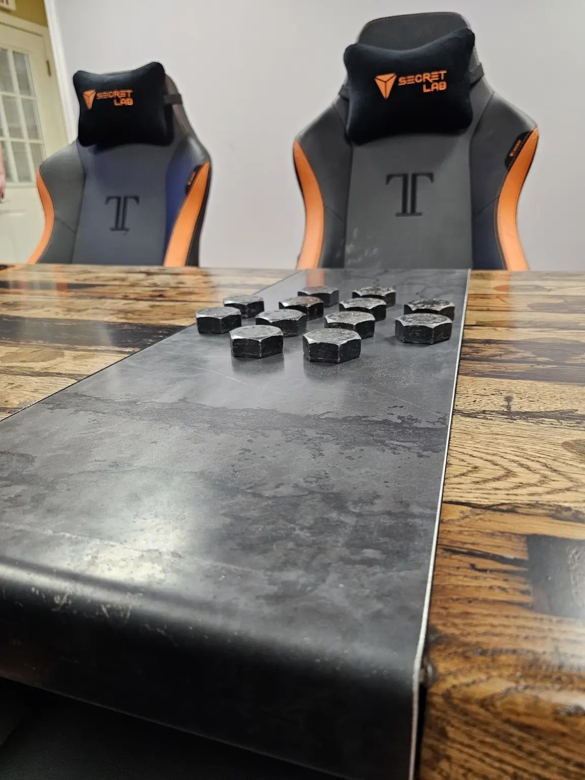 A group of large bolt heads displayed in a dark band across the middle of the conference table.