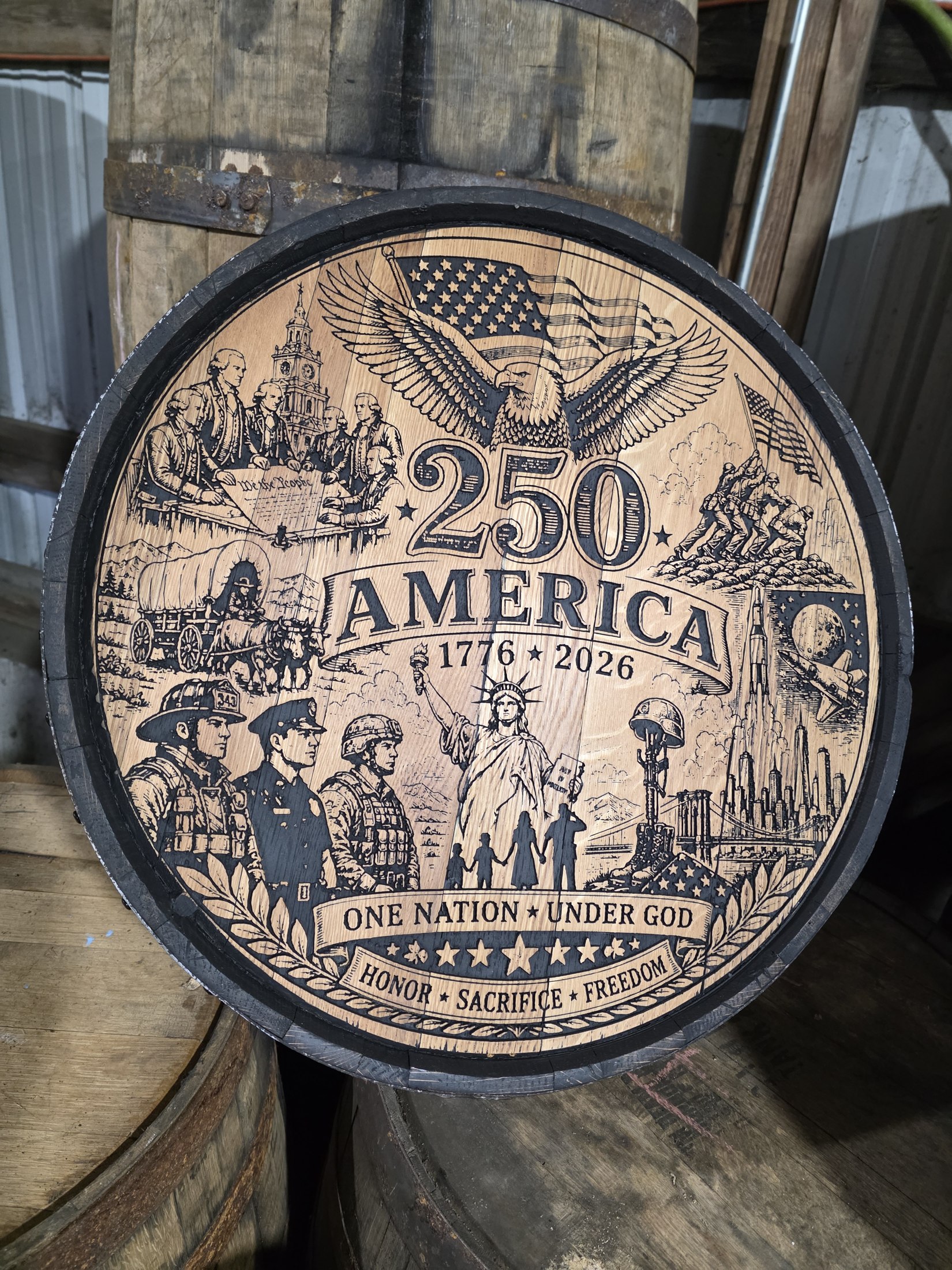 Finished America 250 barrel cap with an eagle, flag, Statue of Liberty and scenes of American service engraved across the wood.