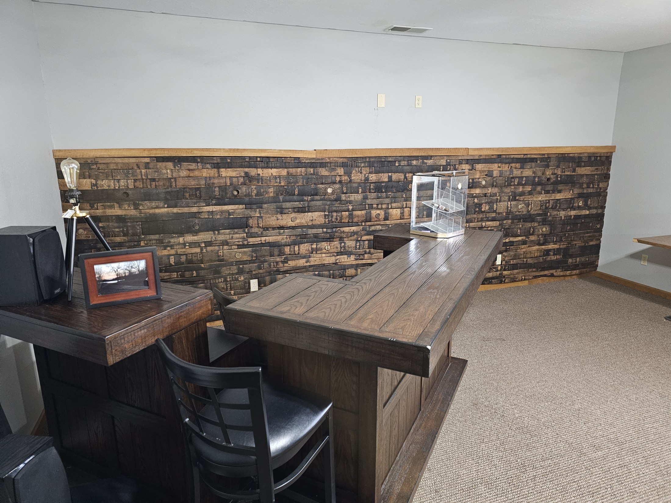 Horizontal wood staves form a feature wall behind a table in a furnished room.