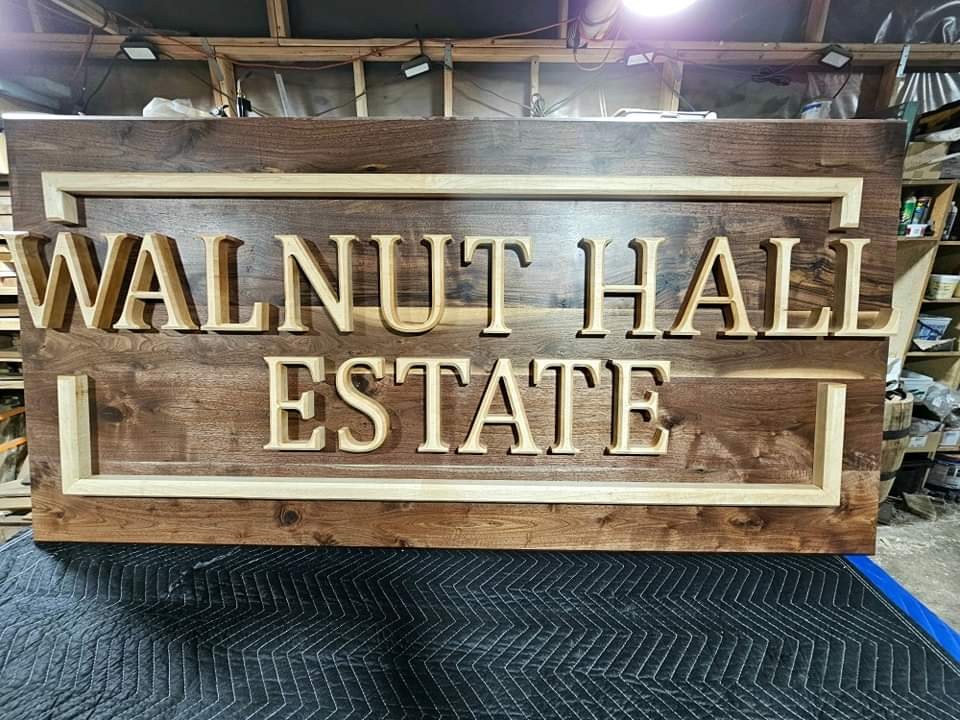 Rectangular Walnut Hall Estate sign with raised light-colored lettering, shown on the shop bench.
