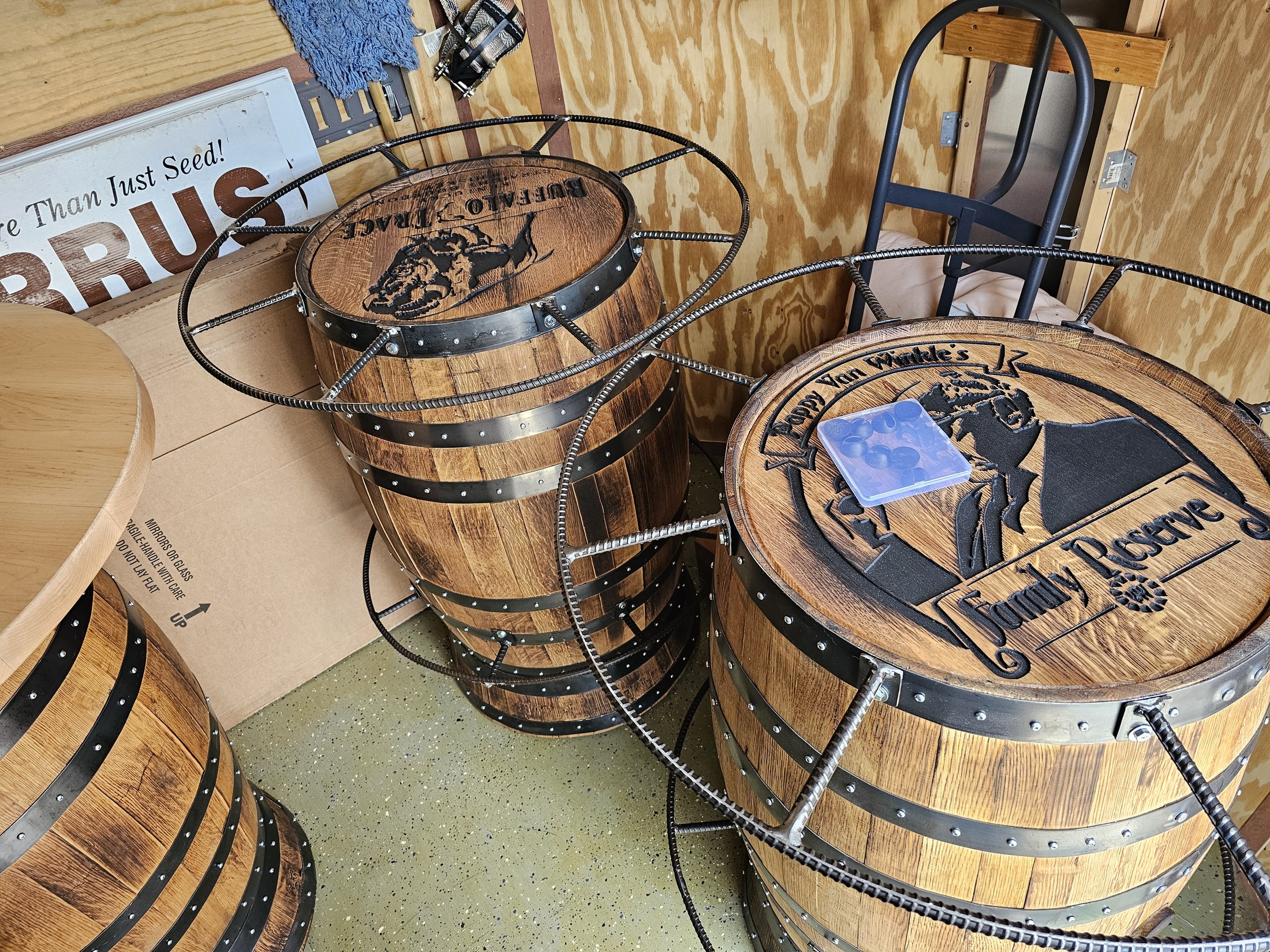 Two engraved barrel cocktail tables with rebar surrounds, glass tops and welded footrests in the workshop.