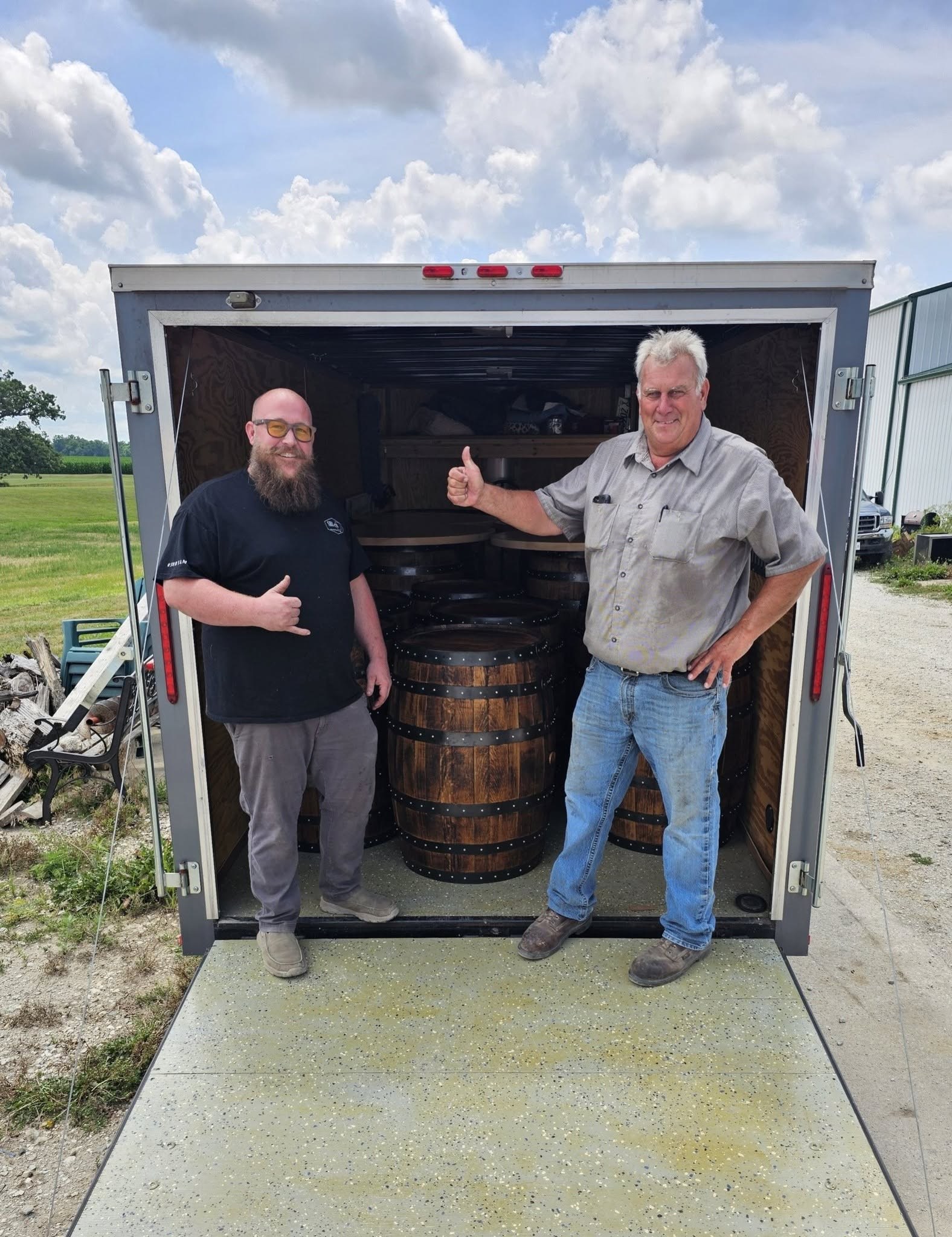 Ryan and the father of the bride stand beside a trailer loaded with the completed barrel tables.