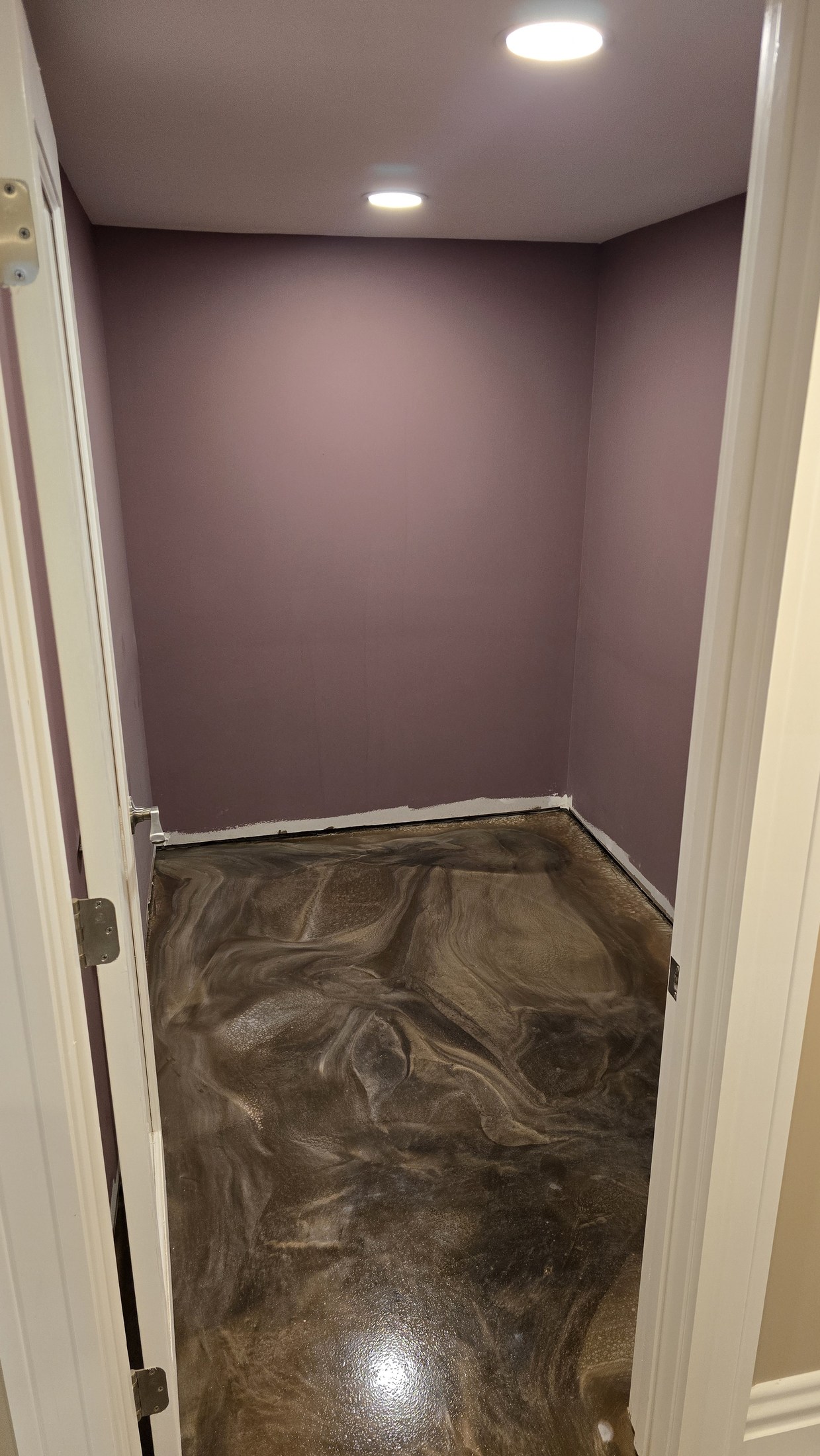 Empty narrow room with mauve walls before custom shelves and vertical bottle racks are installed.