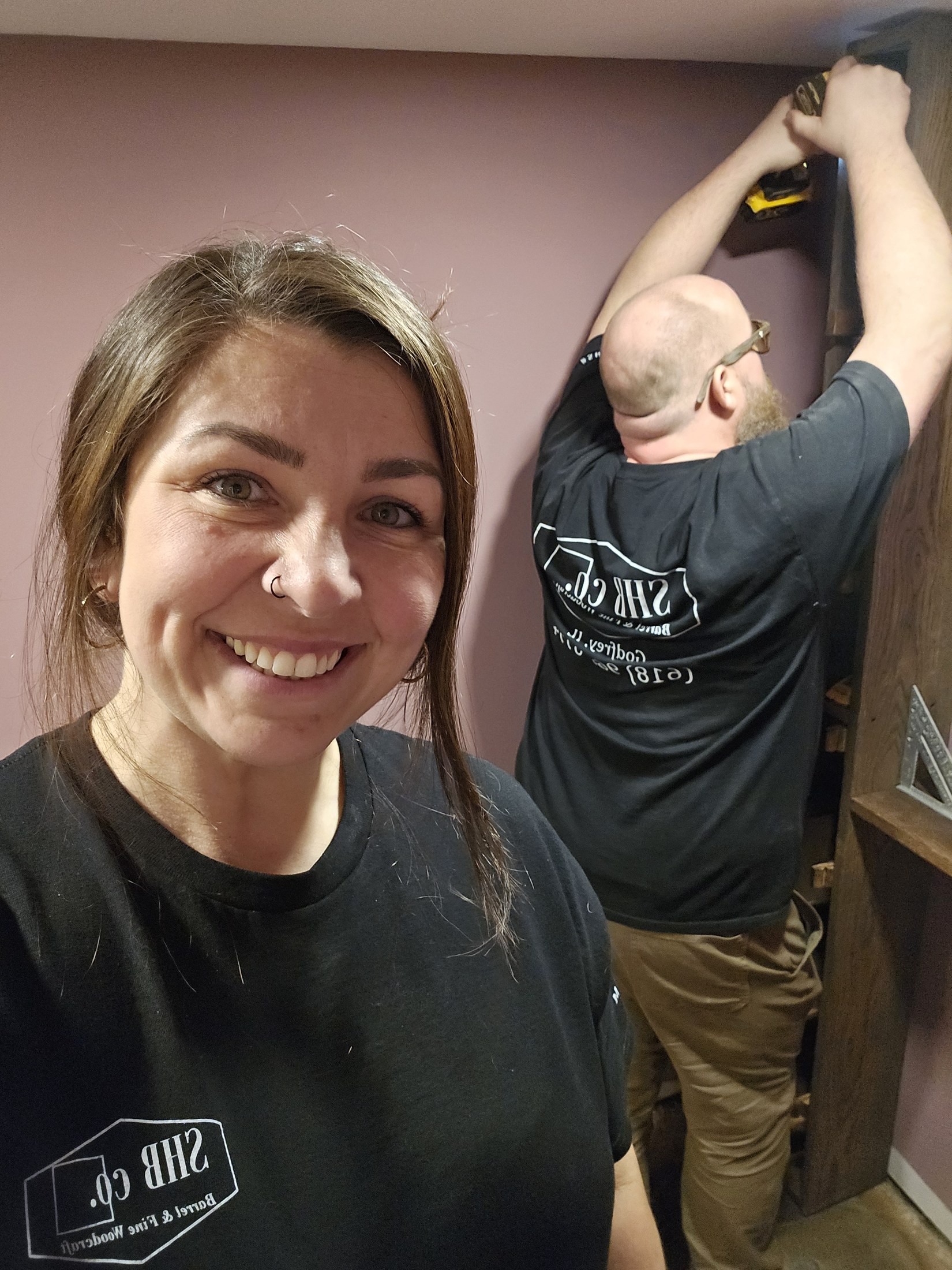 Faith in the foreground while Ryan secures a wood shelf in the room behind her.
